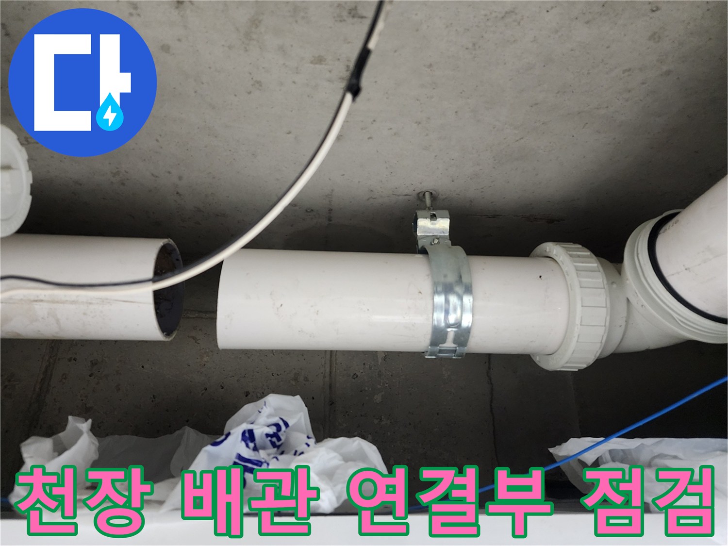 천장 콘크리트 구조물에 설치된 흰색 배관과 금속 클램프 상세 모습