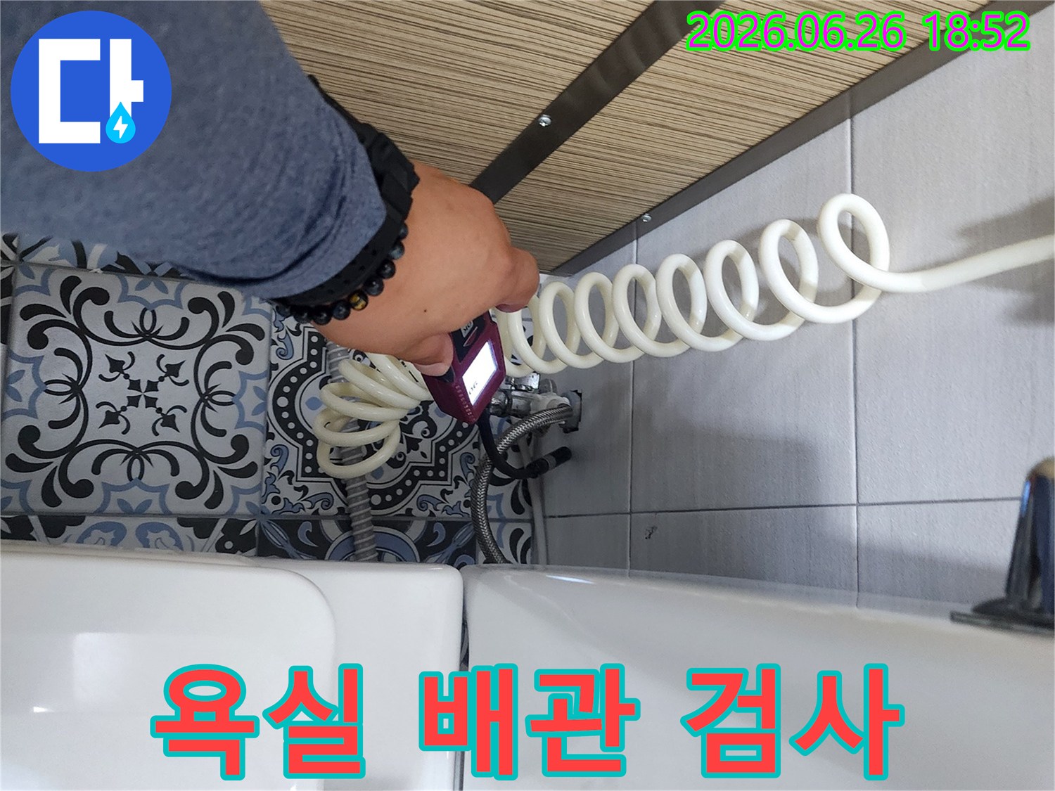 누수 엔지니어가 욕실 변기 옆 배관에서 누수 여부를 확인하기 위해 장비를 사용하고 있습니다.