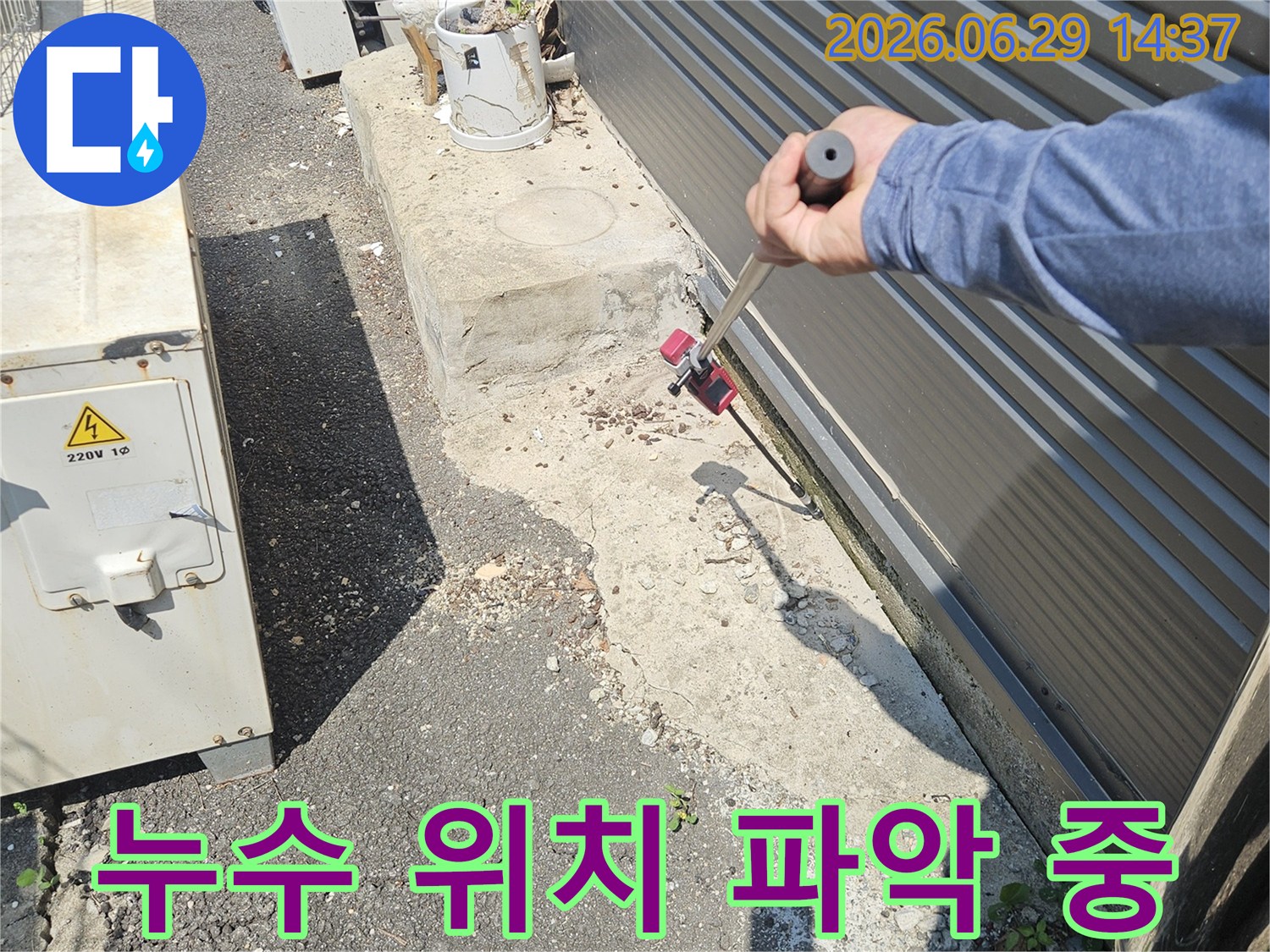 누수 엔지니어가-정확한 누수 위치를 파악하기 위해-전문 탐지 장비를 사용하여-건물 외벽을 세밀하게 점검하고 있습니다.