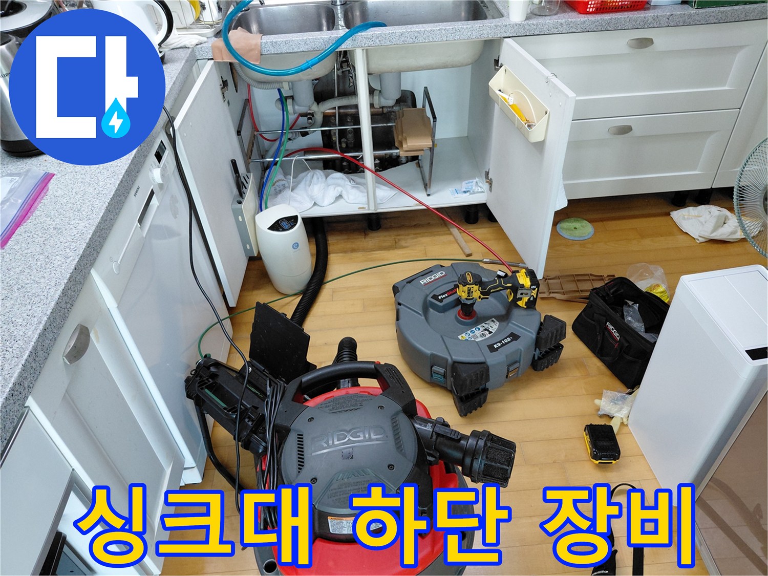 작업 현장의 싱크대 밑-배관 세척을 위한 석션기와 각종 공구들