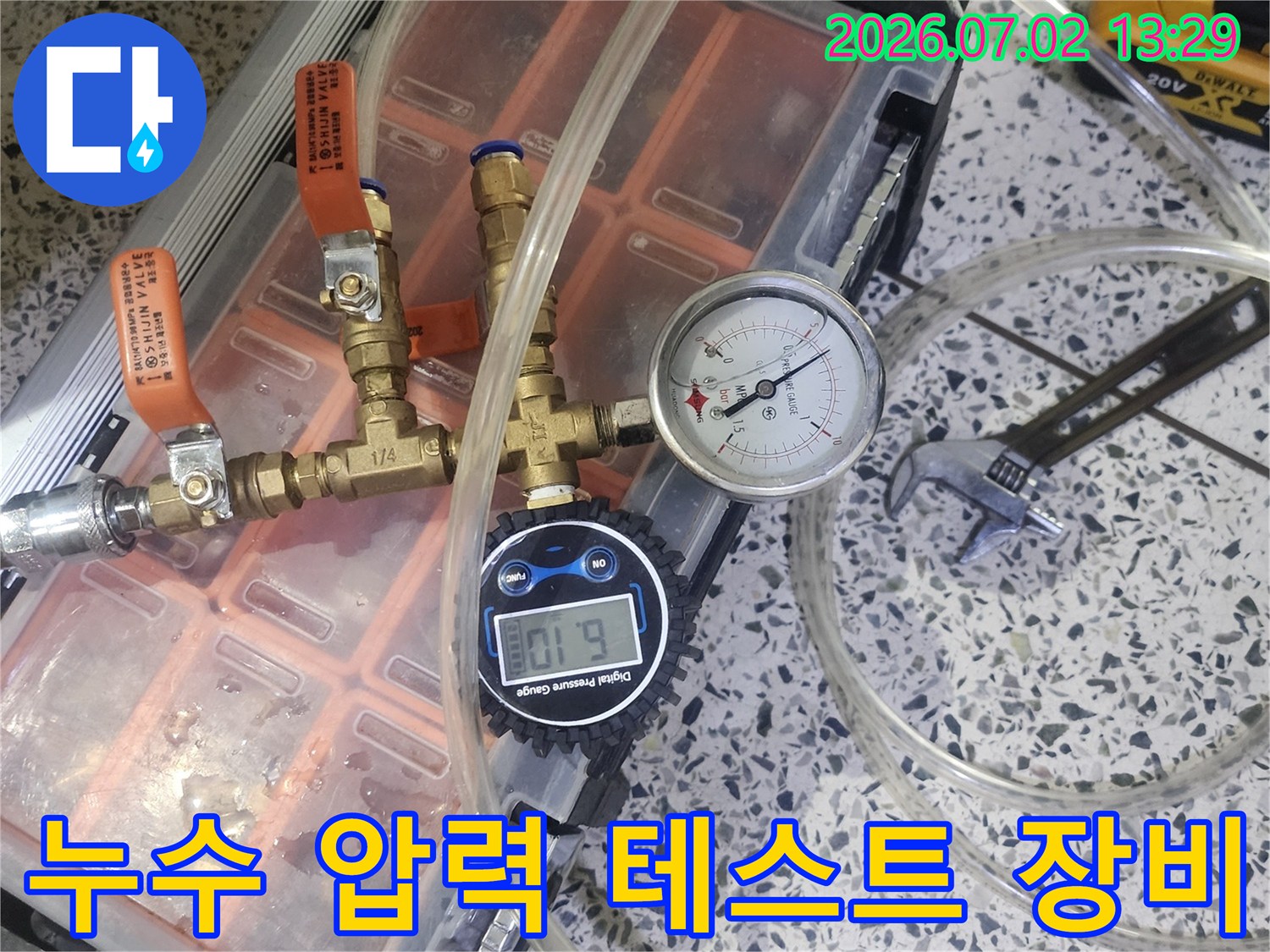 누수 탐지를 위해 압력 게이지와 밸브-튜브가 연결된 장비를 사용하여 배관 압력을 측정하는 모습입니다