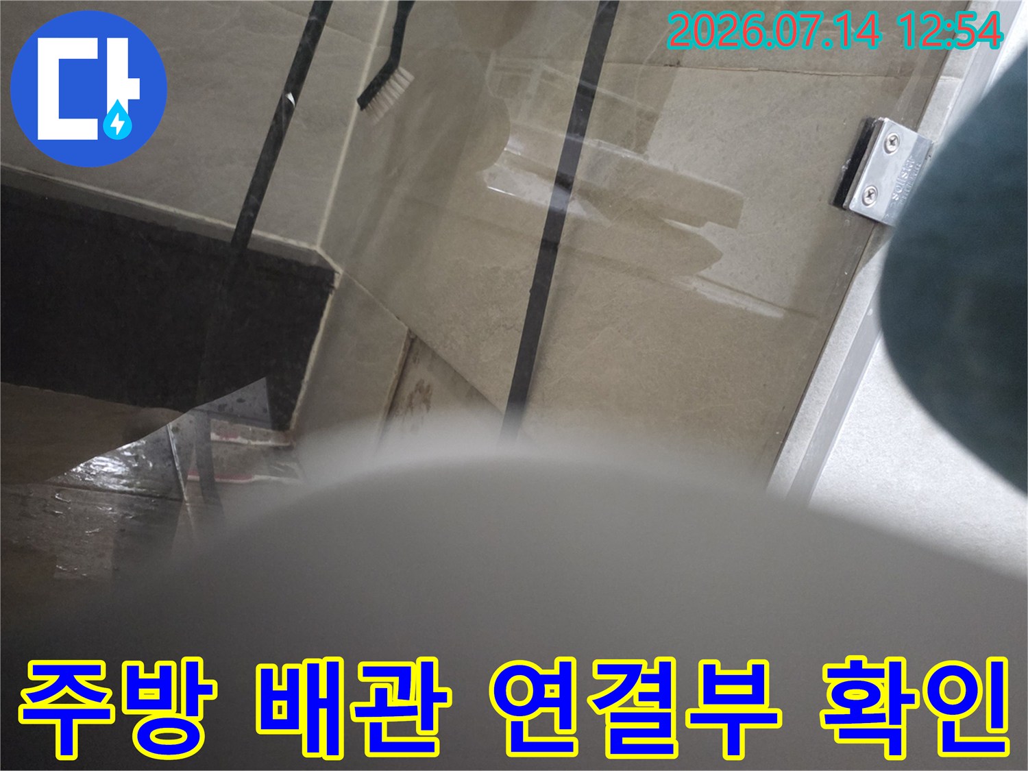 싱크대 하단부의 물샘 흔적과 노출된 배관 연결 부위를 촬영한 사진입니다.