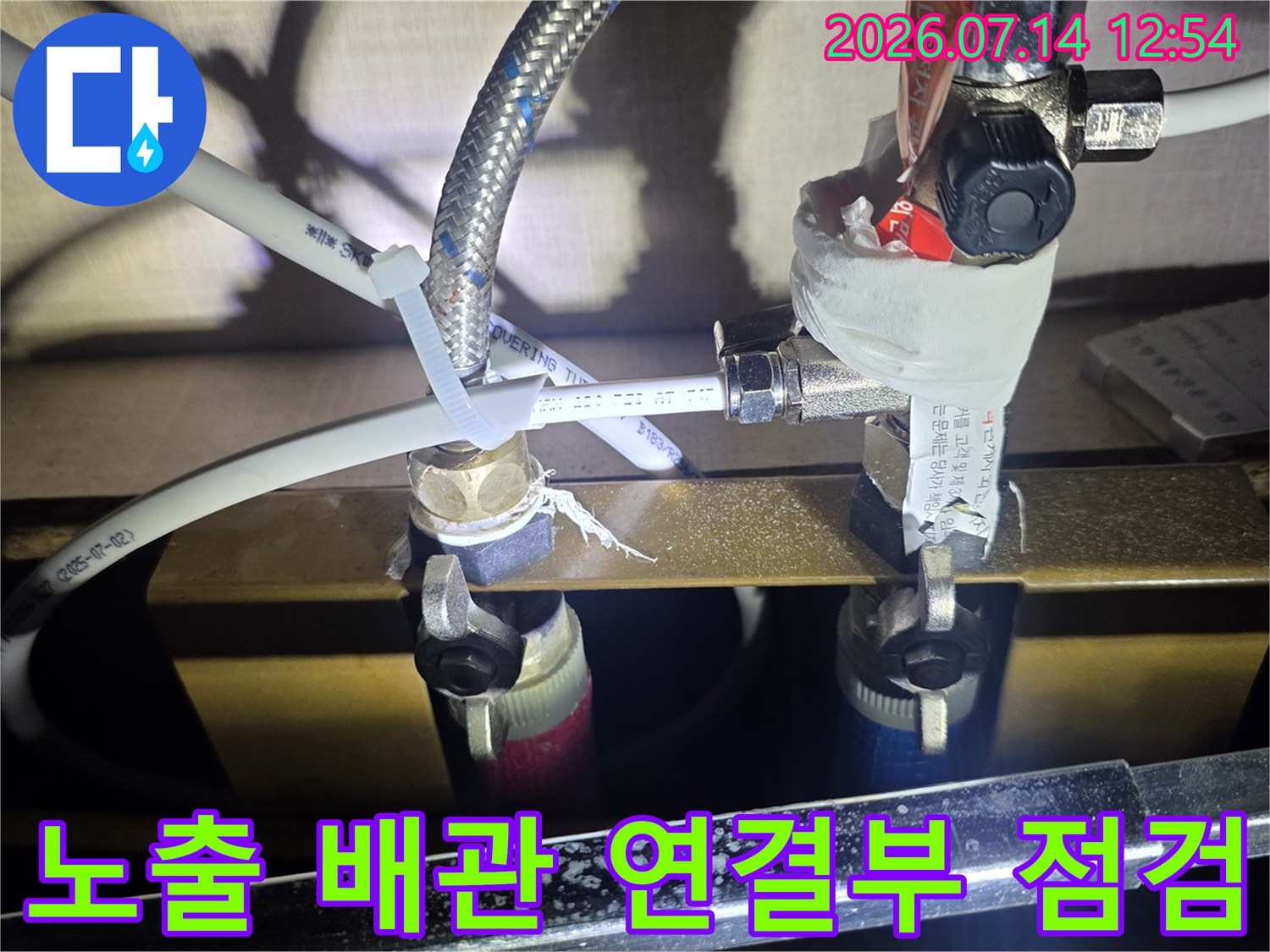 싱크대 하부의 노출된 수도 배관 연결부를 압력 게이지와 함께 촬영한 사진