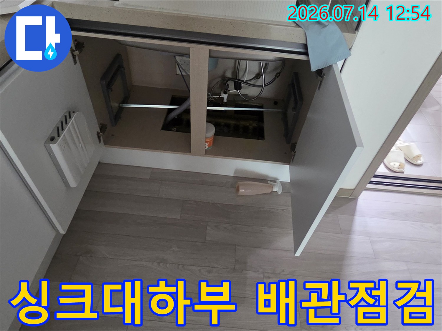 싱크대 하부장을 열고 노출된 수도 배관 연결 부위를 점검하는 모습