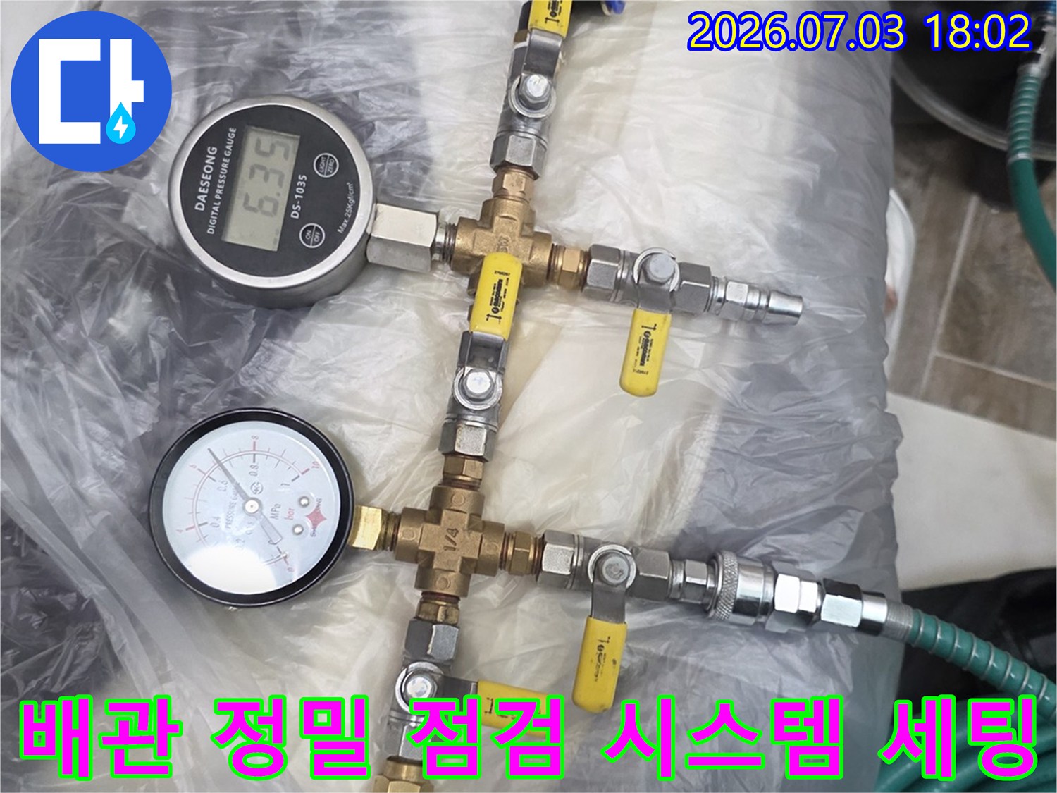 두 개의 게이지와 호스가 연결된 배관의 기밀 상태 측정 장비