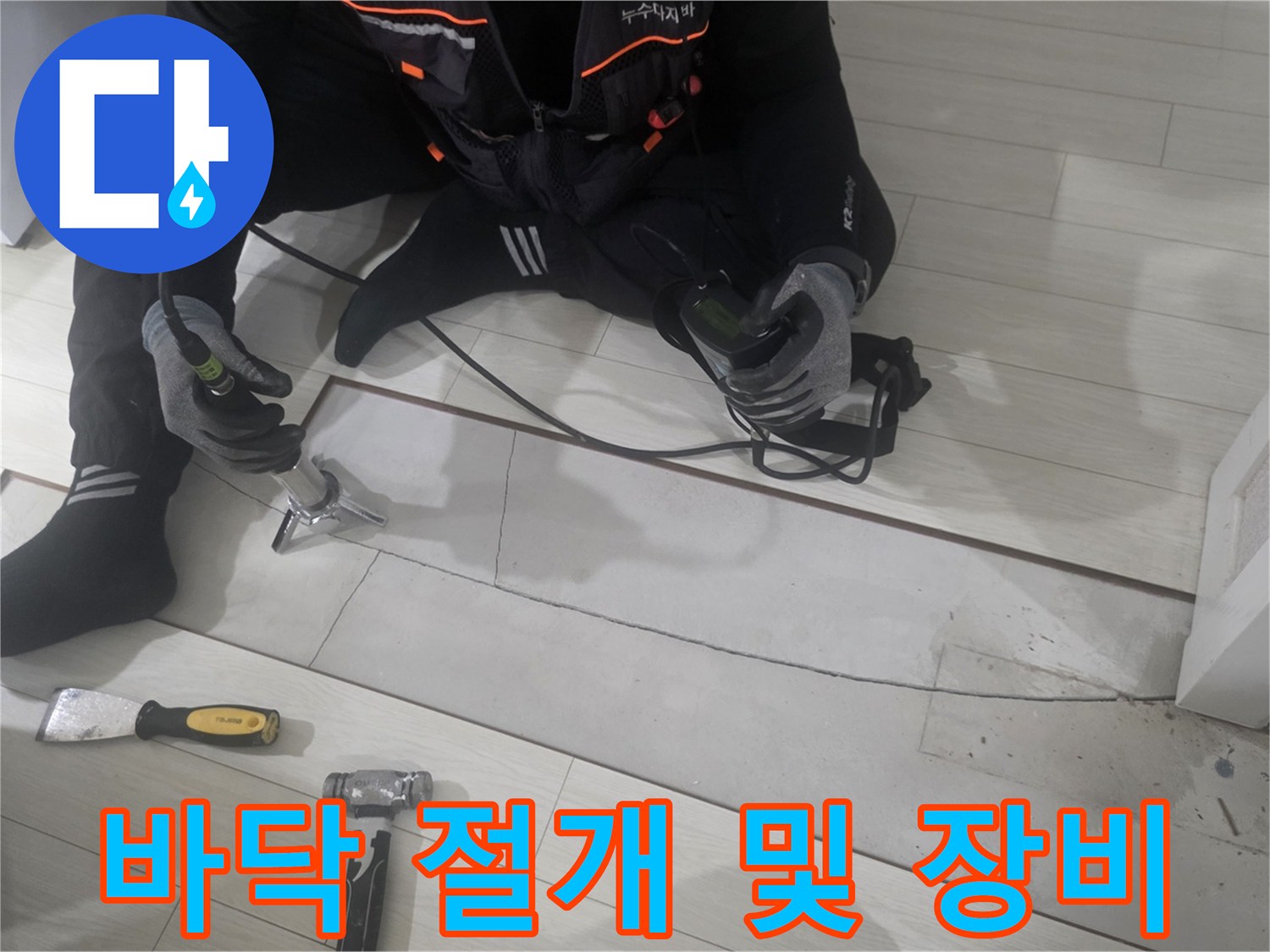 강마루를 절개하고 배관을 확인하기 위해 전동 공구와 망치를 준비한 현장 사진입니다.