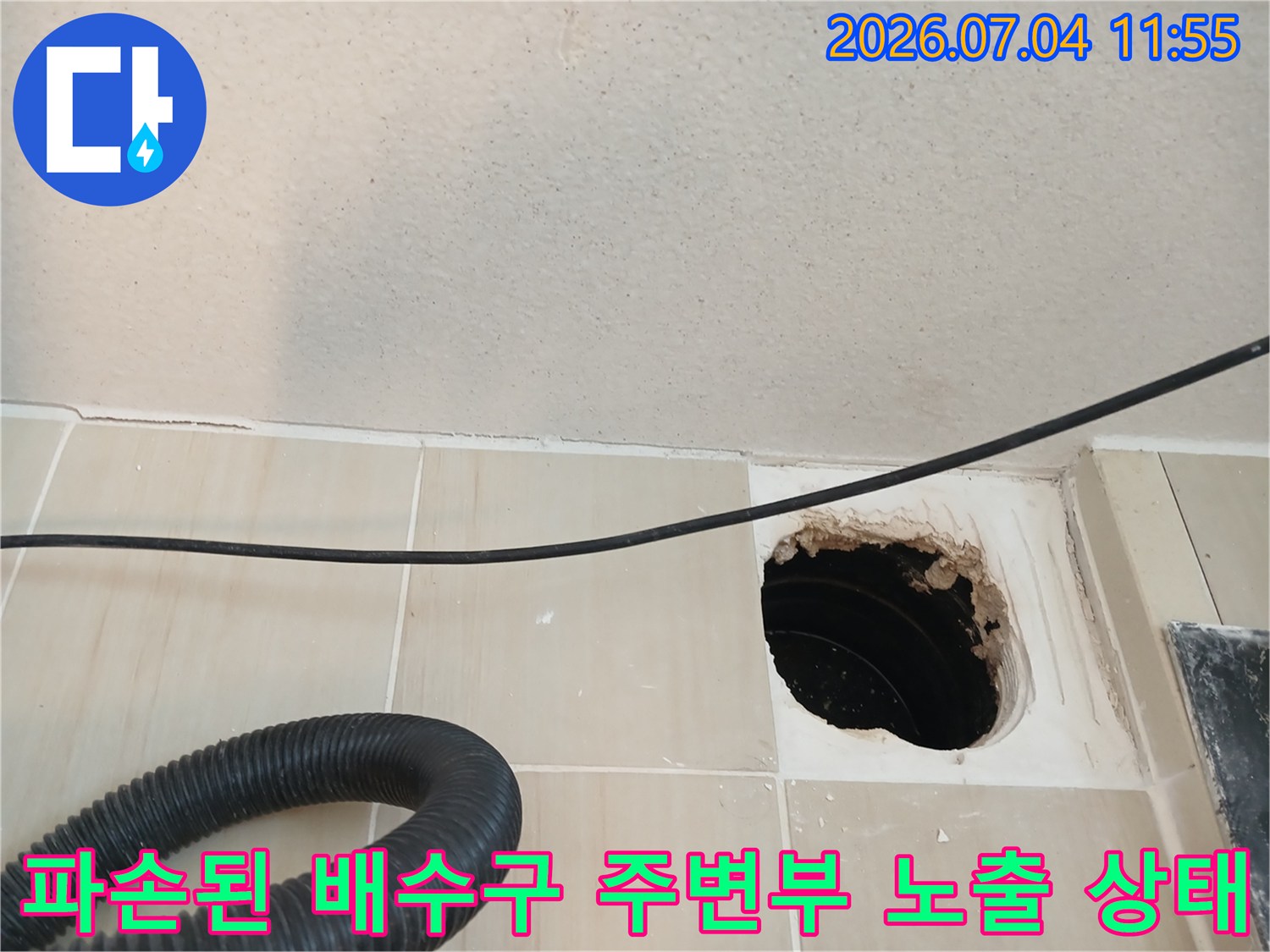배수구 주변의 깨진 마감재와 내부 구조물이 드러난 모습