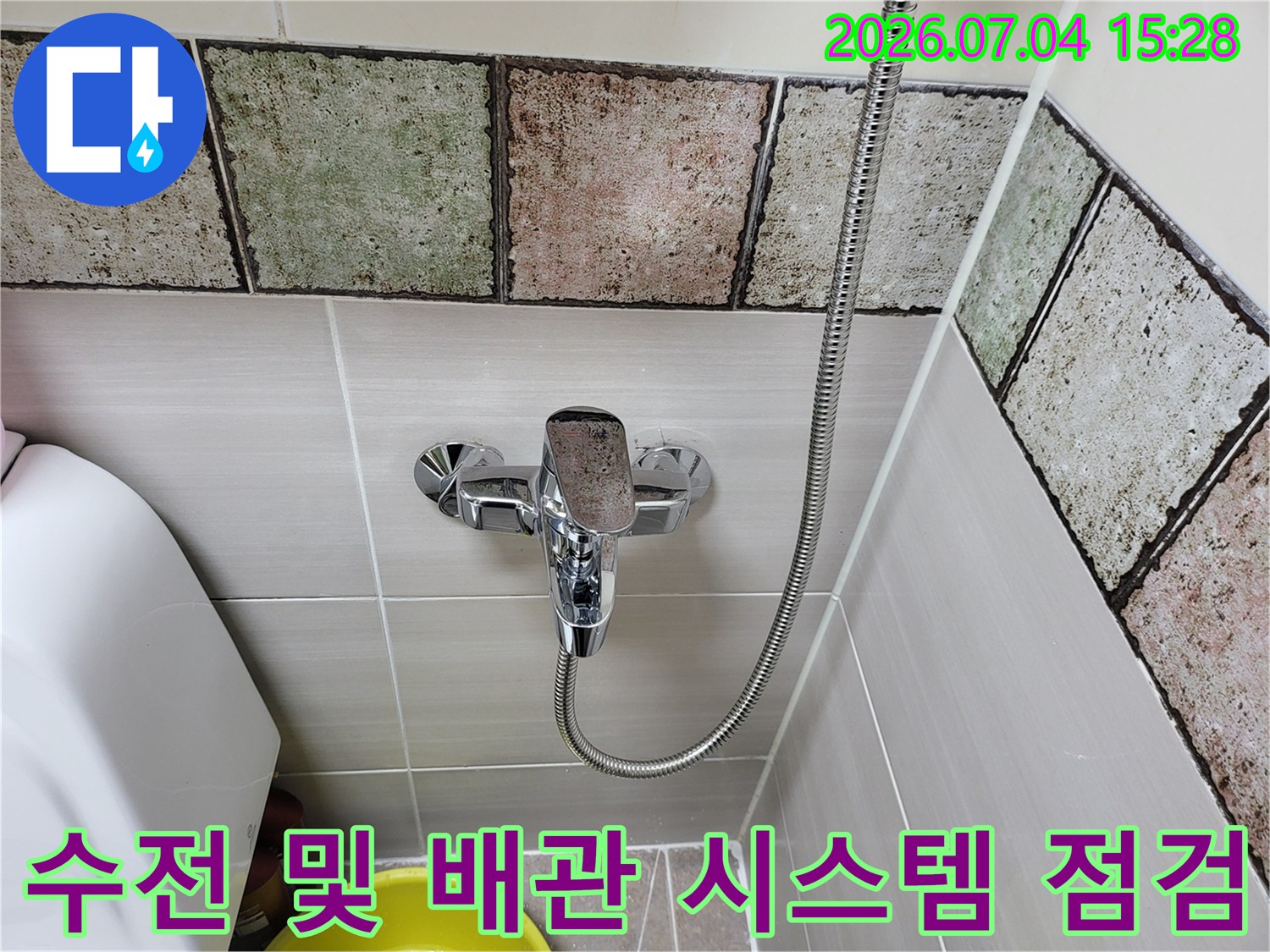 욕실 벽면 타일과 샤워용 수품의 연결 상태를 촬영한 사진