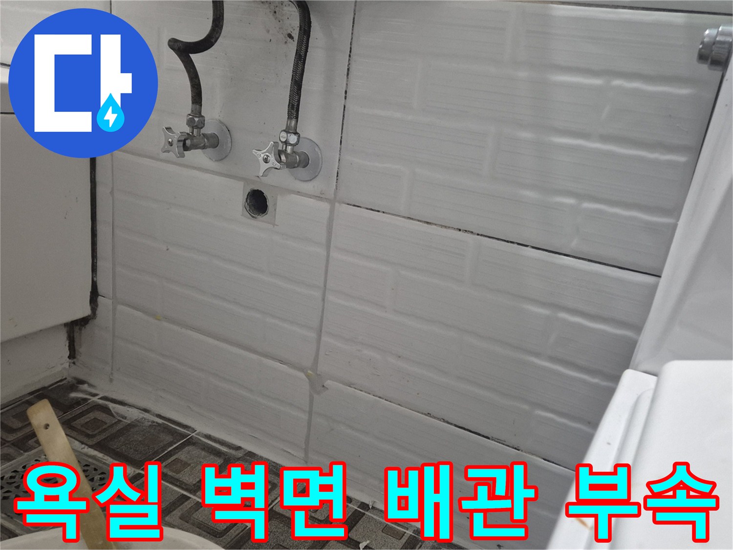 화장실 벽면에 설치된 수도꼭지와 연결 배관의 상태를 보여주는 사진입니다.