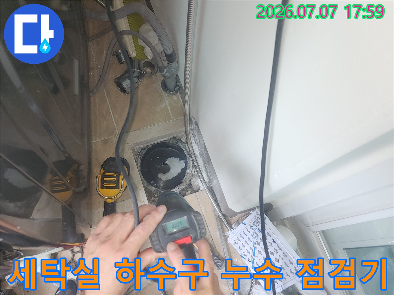 측정 장비를 사용하여 세탁실 배수구 주변을 점검하는 사진