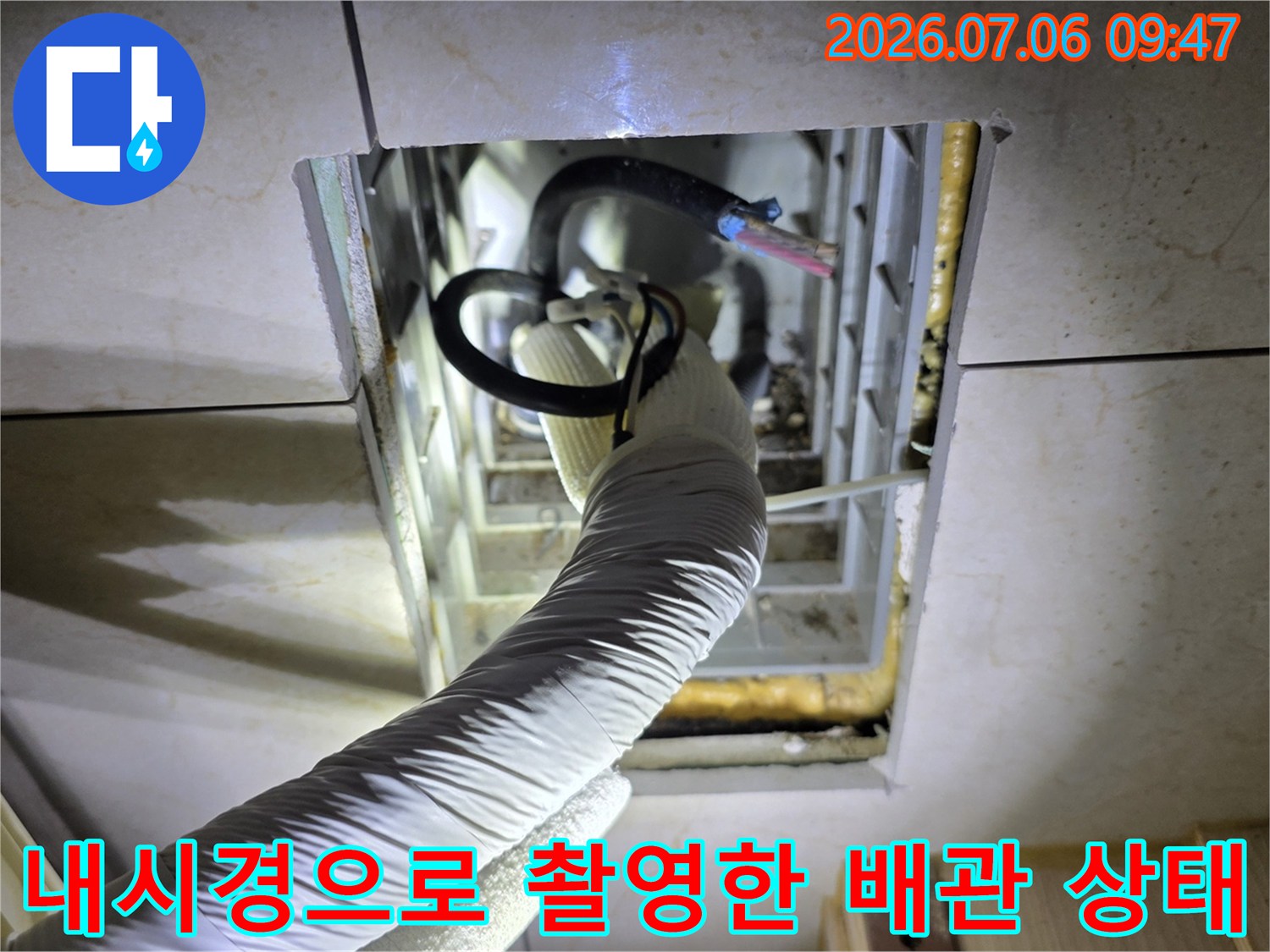 어두운 천장 내부 공간에서 내시경을 이용해 에어컨 배관 시스템의 결함을 찾아내는 모습