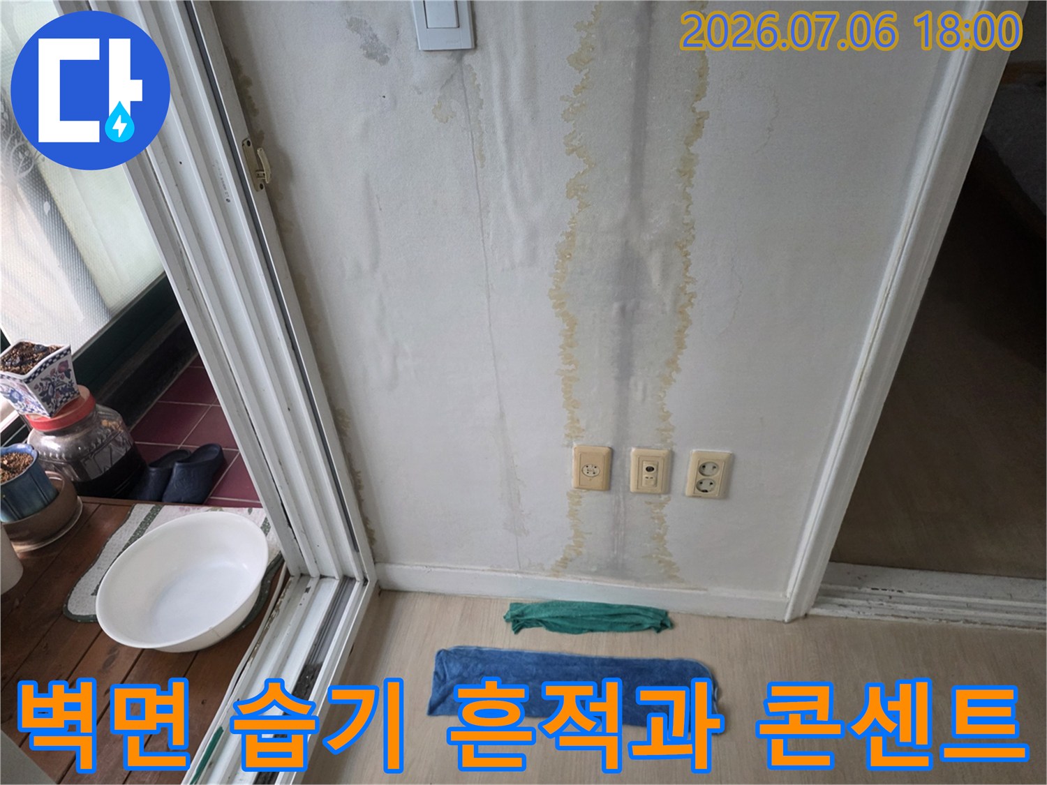 벽면에 가로로 길게 번진 누수 습기 자국과 아래쪽 전원 콘센트 모습