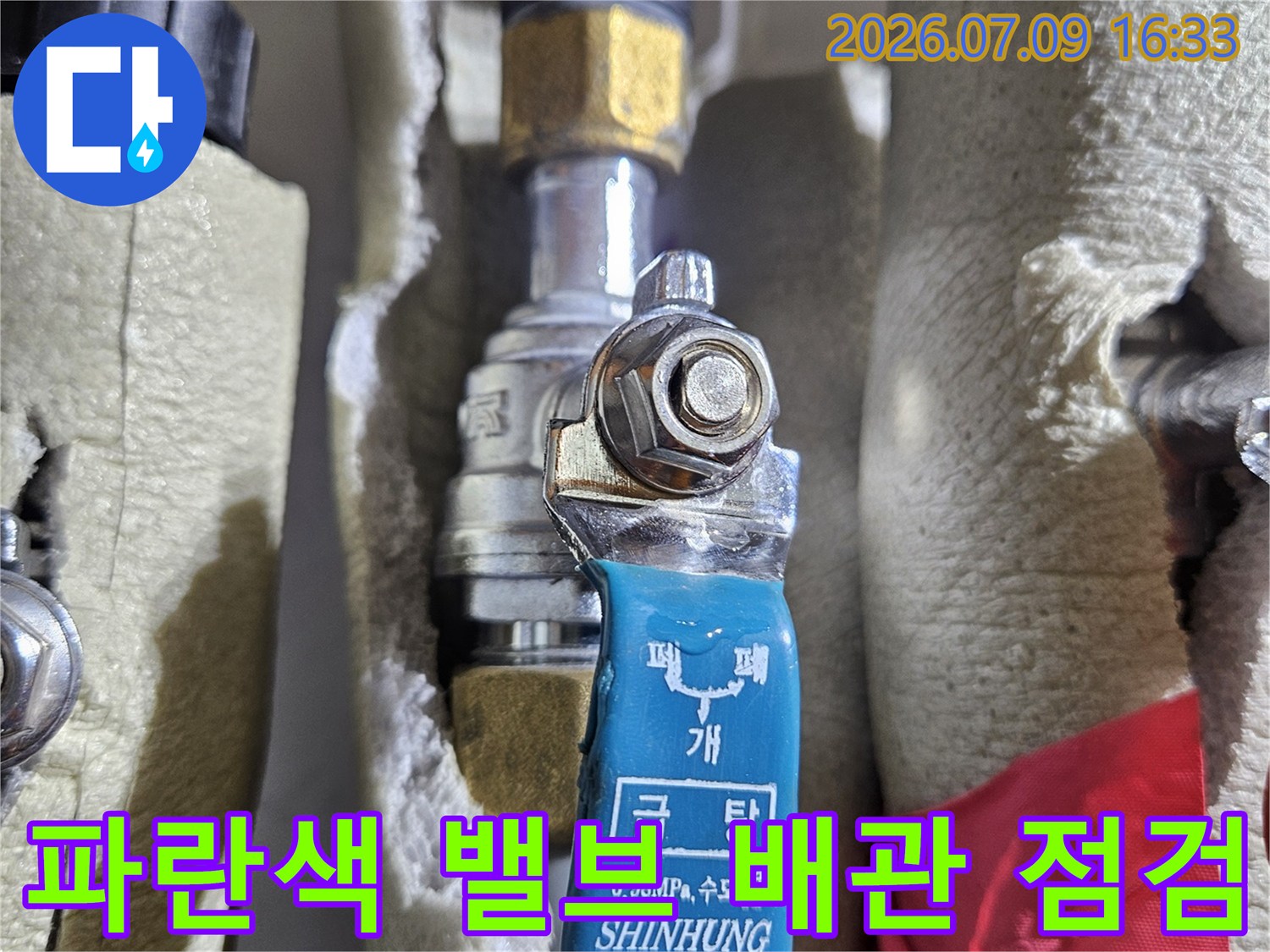 보호재로 감싸진 배관과 파란색 라벨이 붙은 온수 밸브 부분