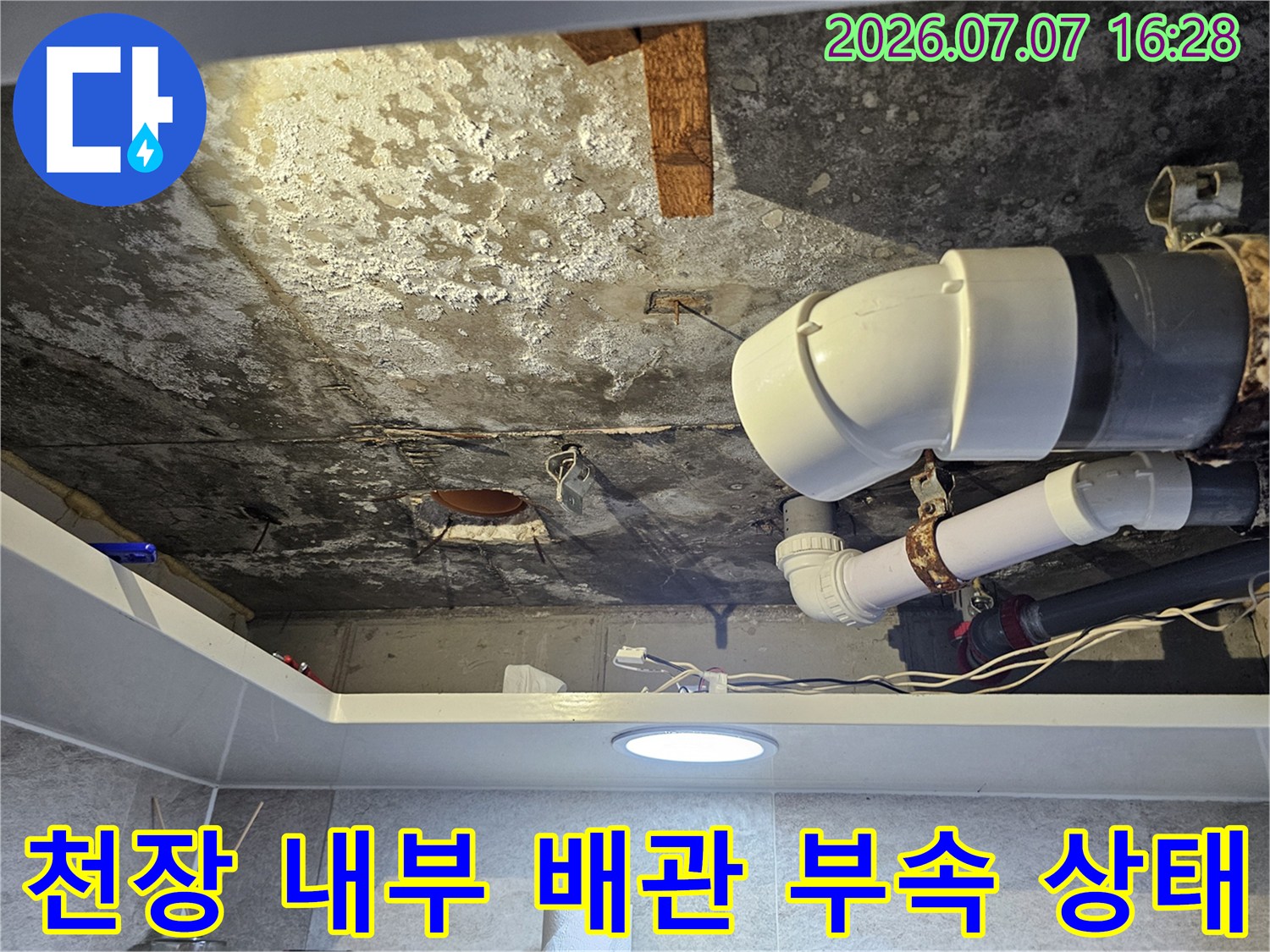화장실 천장 속 노출된 배출용 파이프와 연결 호스 세부 모습