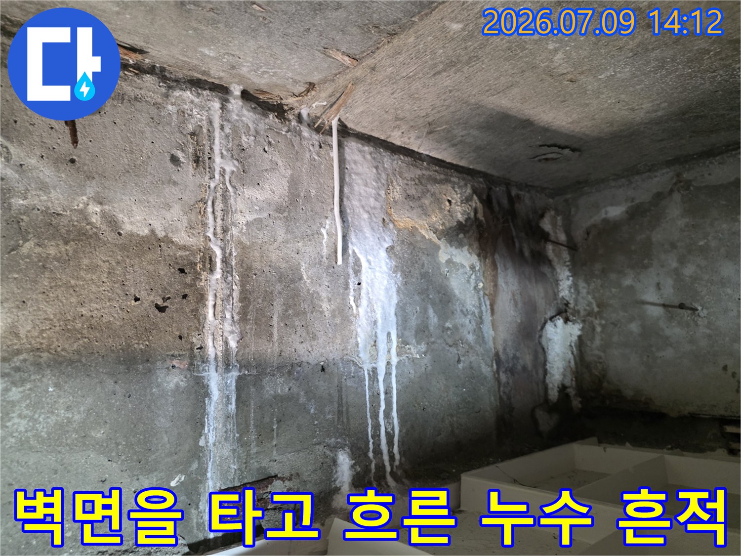 콘크리트 벽면에 형성된 하얀색 석회 성분의 누수 트랙과 노출 된 마감재 일부