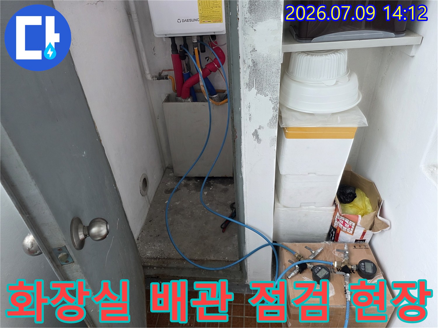 화장실 내부 배관에 연결된 파란색 호스와 계측 장비가 배치된 모습