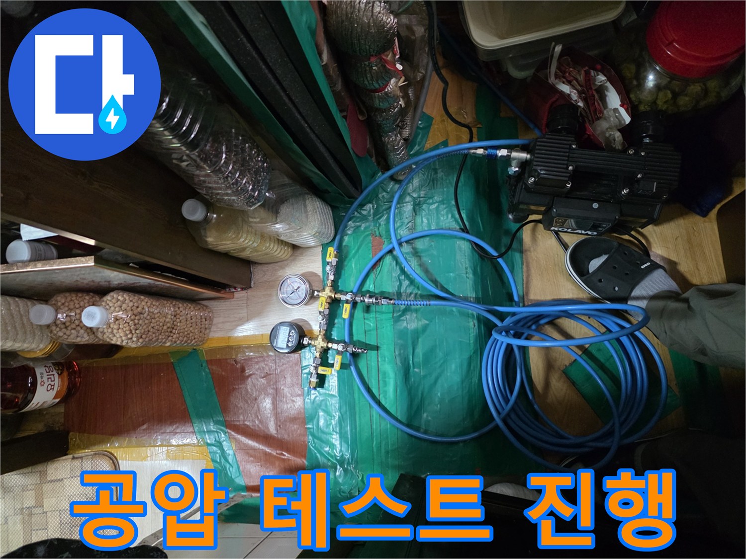 파란색 호스와 압력계를 사용하여 - 배관의 기밀성을 점검하는 장면