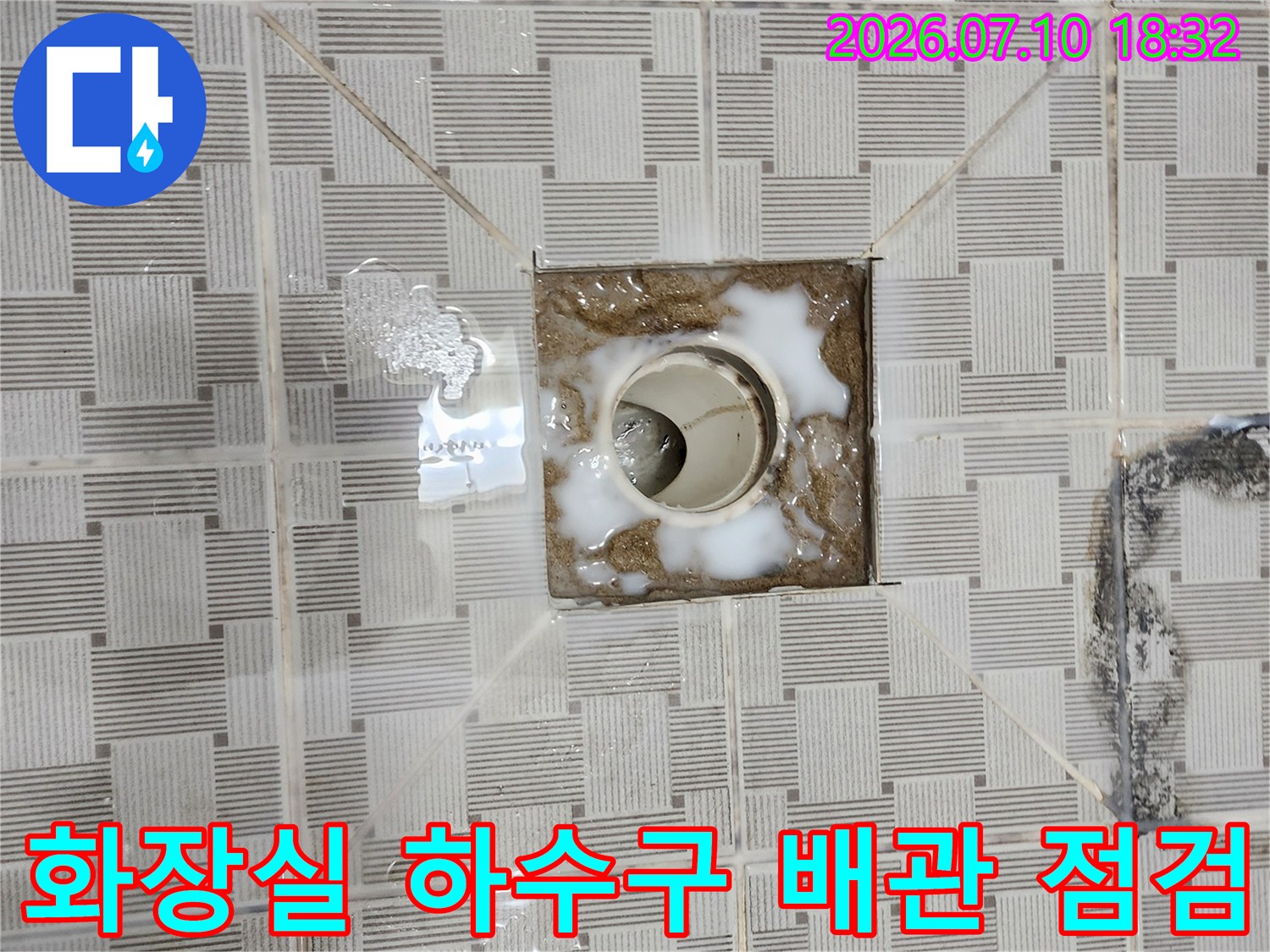 배수구 주변의 노후된 타일과 오염된 하수관 연결 부위 모습