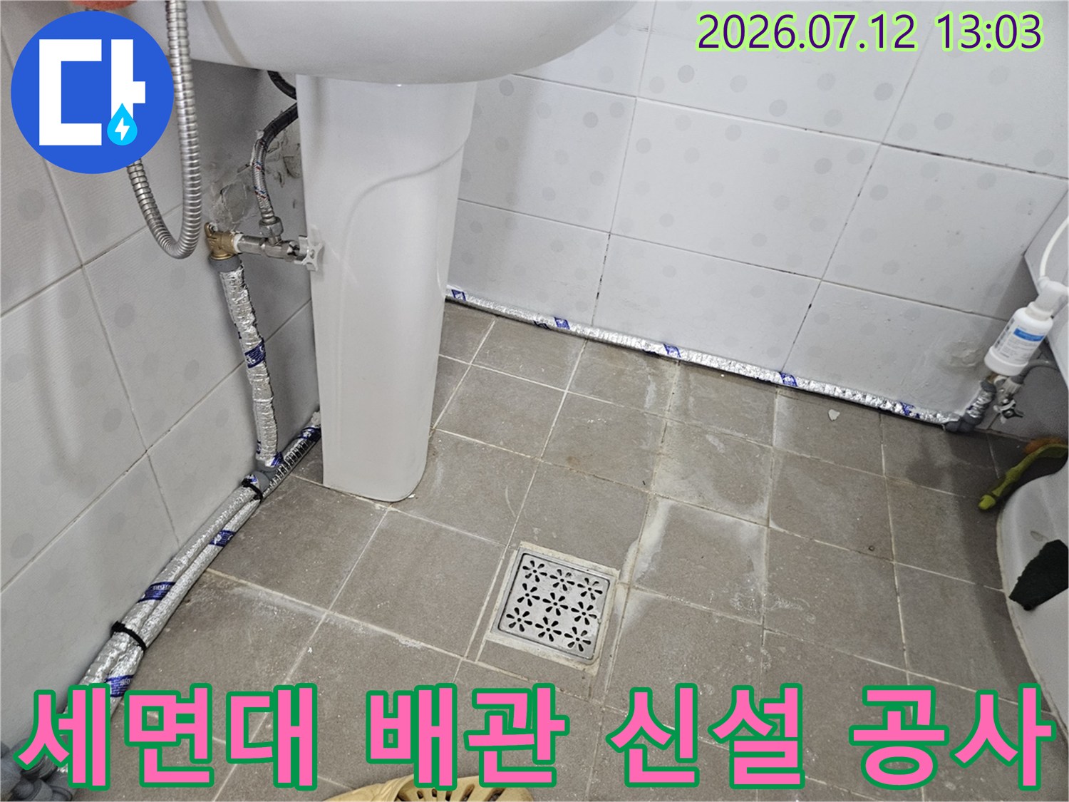 보온재로 덮인 세면대용 직수 배관과 바닥 유입구 주변 시공 모습