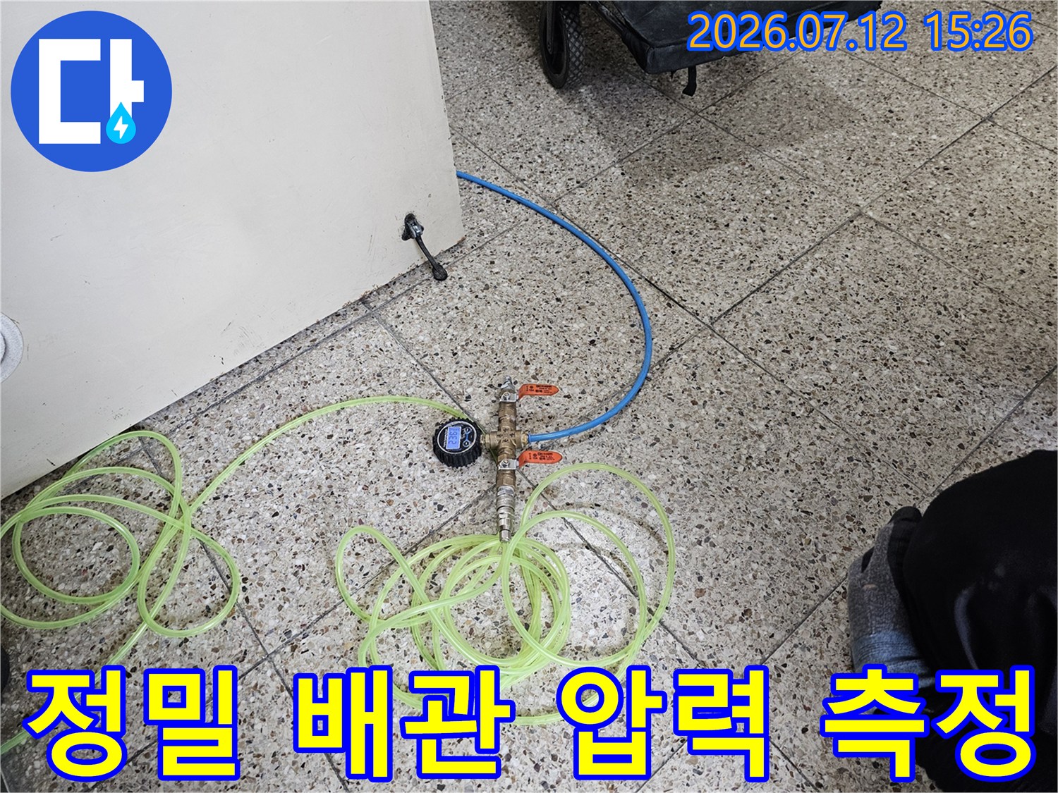 노란색 호스와 파란색 배관이 연결된 상태에서 게이지로 수치를 확인하는 전문 누수 진단 모습