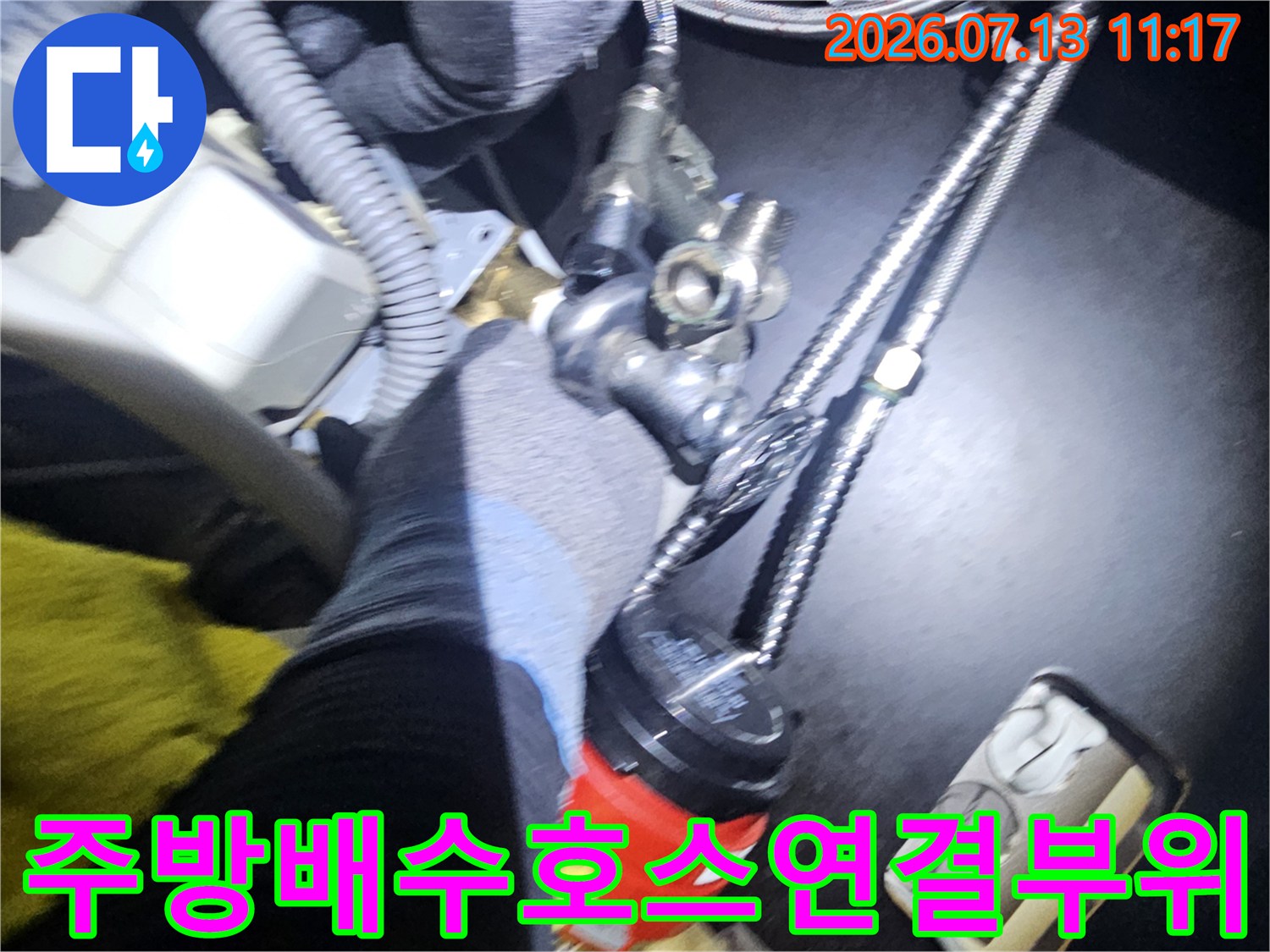 은색 금속 주름관과 플라스틱 연결 부품이 설치된 싱크대 하단 설비 사진