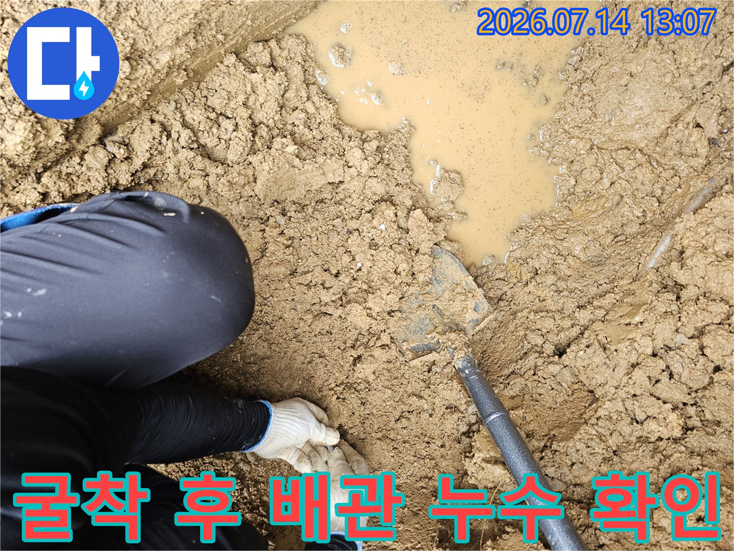 공사 현장에서 흙을 파내고 노출된 물 젖은 배관 부위를 점검하는 장면