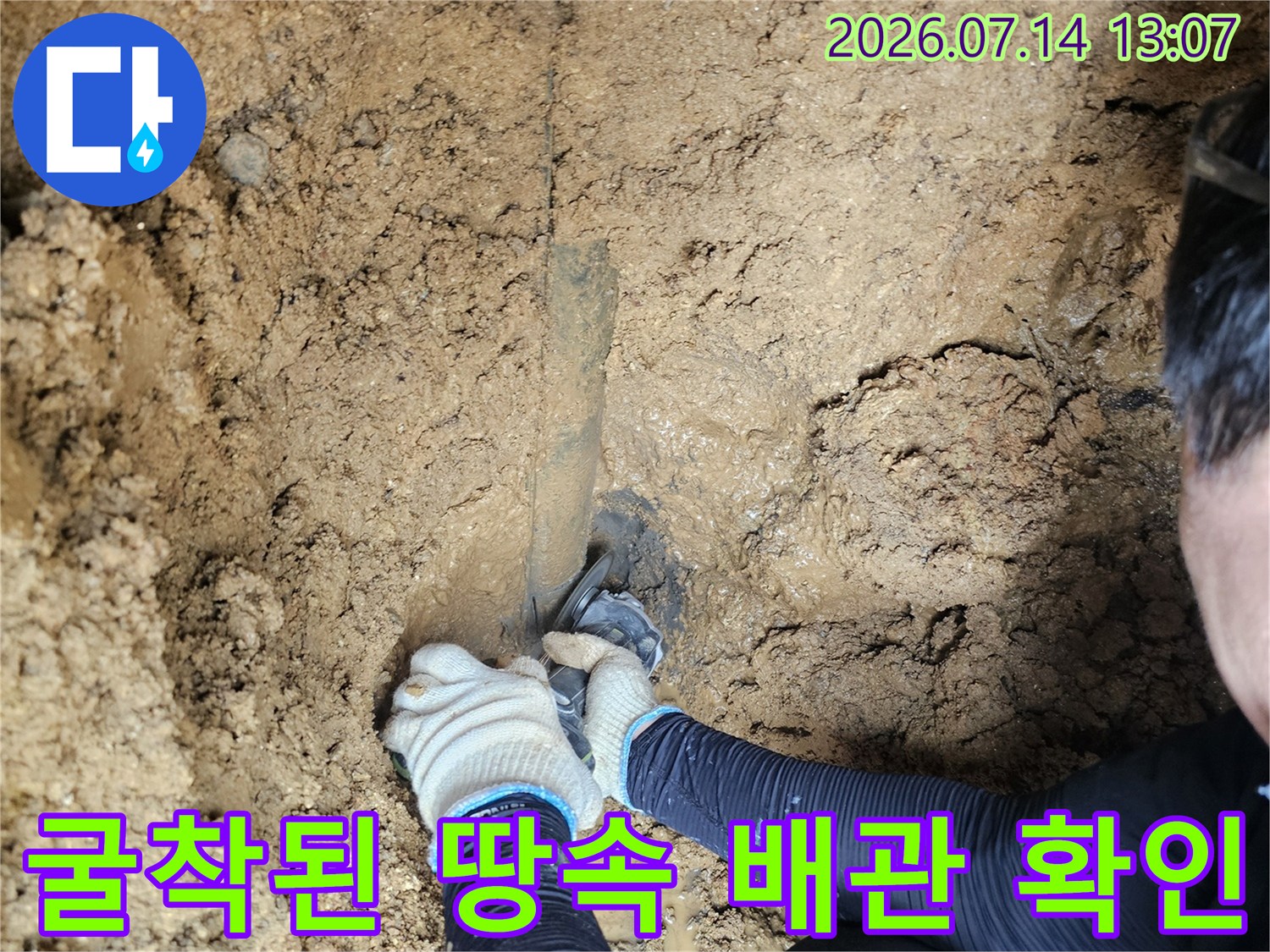 흙을 파내어 노출시킨 수도 배관의 누수 지점을 점검하는 모습