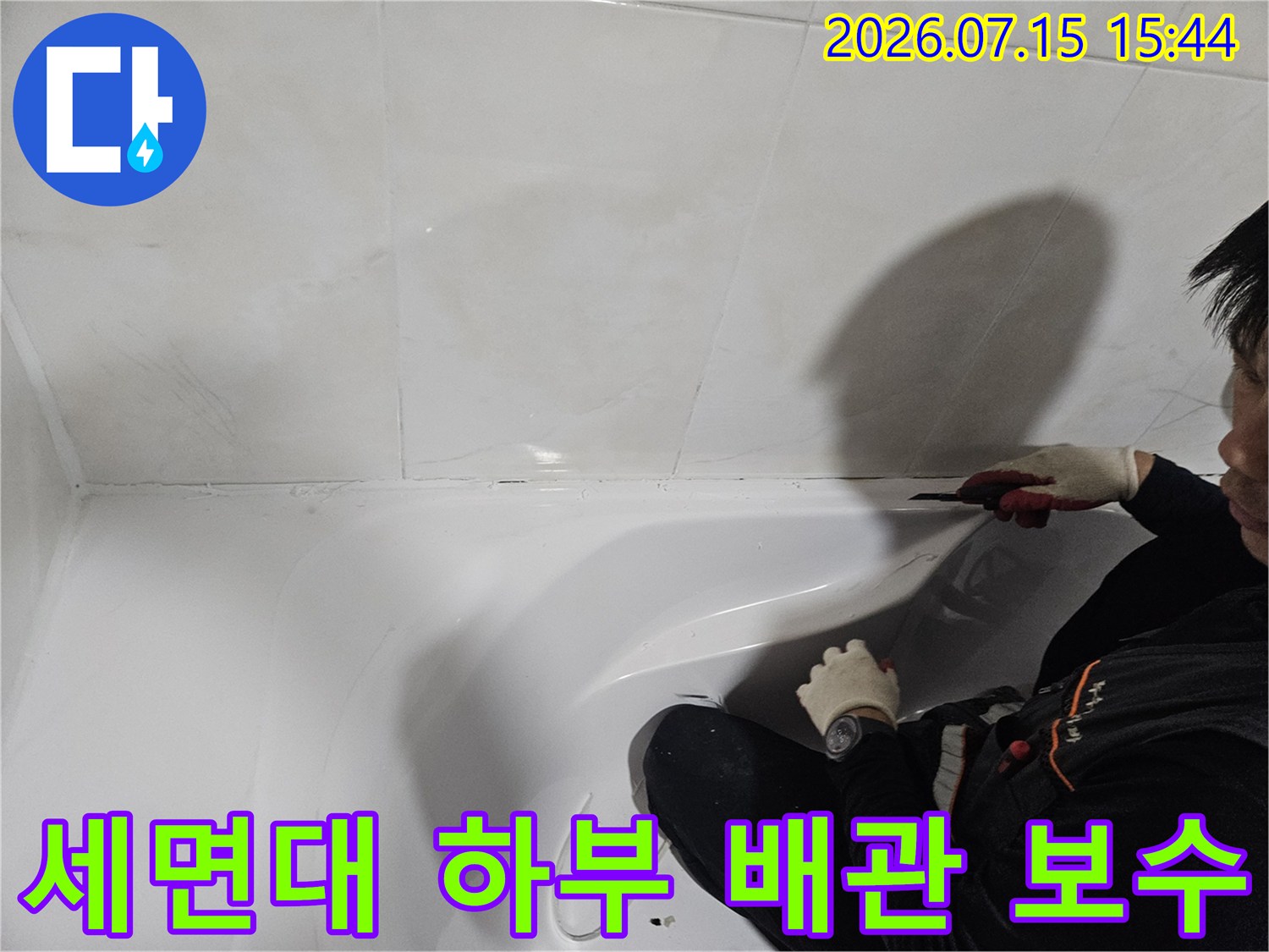 기술자가 세면대 밑 공간에서 누수가 의심되는 배관 부위를 점검하는 사진