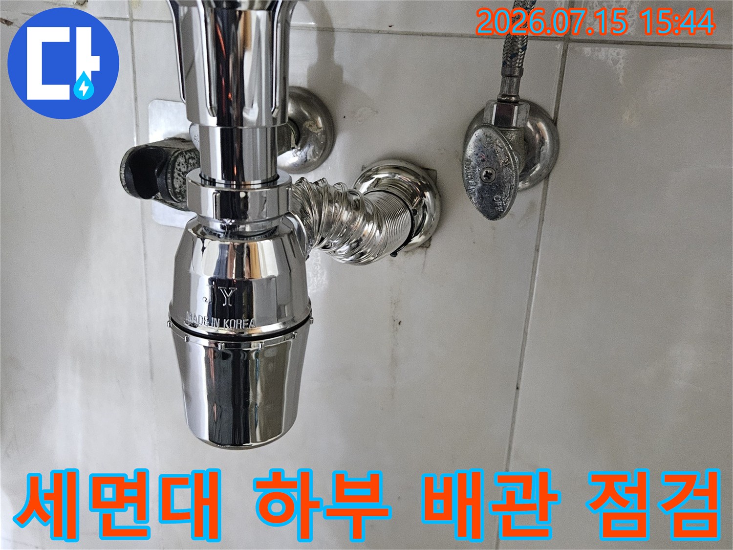 세면대 아래쪽 노출된 은색 금속 배관과 연결 부위의 상세 모습