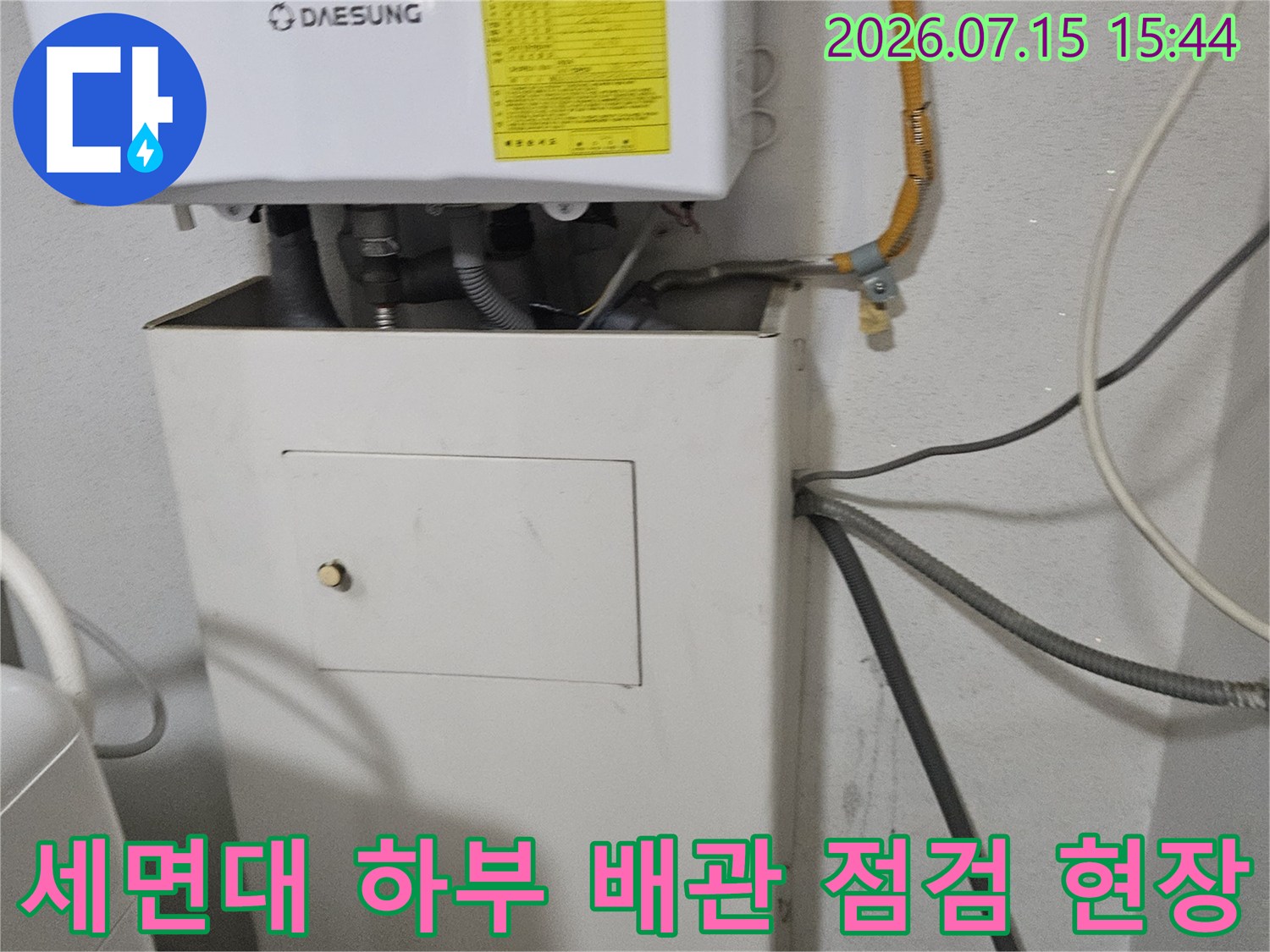 세면대 아래쪽의 노출된 수도배관 연결 상태를 세밀하게 조사하는 모습
