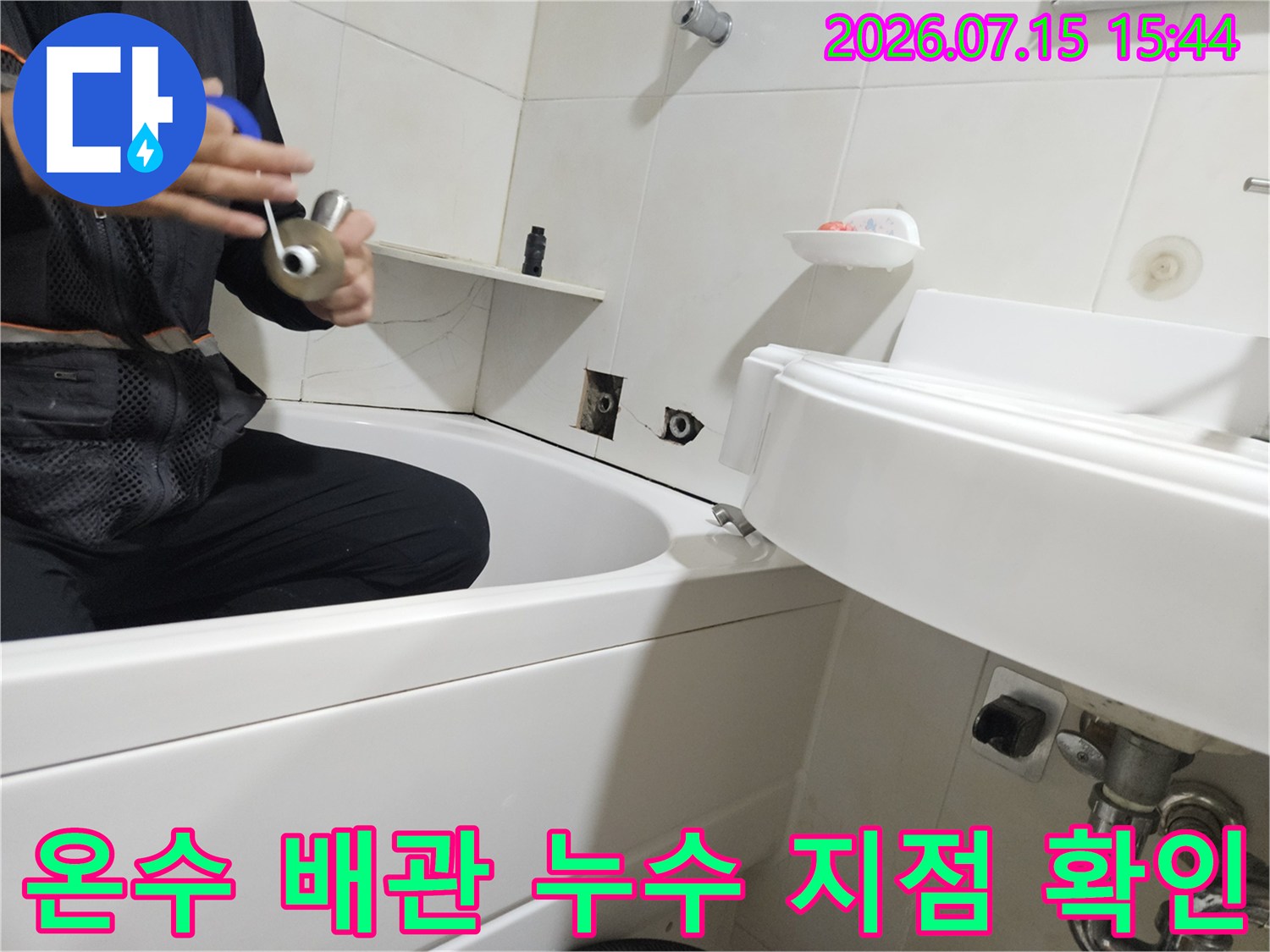 청음식 탐지기를 사용하여 세면대 아래 온수 배관을 점검하는 모습