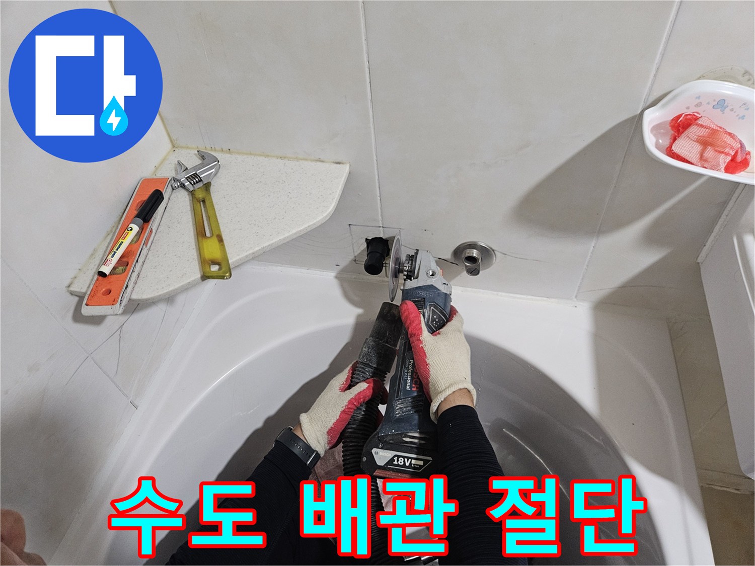 화장실 벽면 배관의 부식된 구간을 제거하기 위해 커터를 사용하는 장면