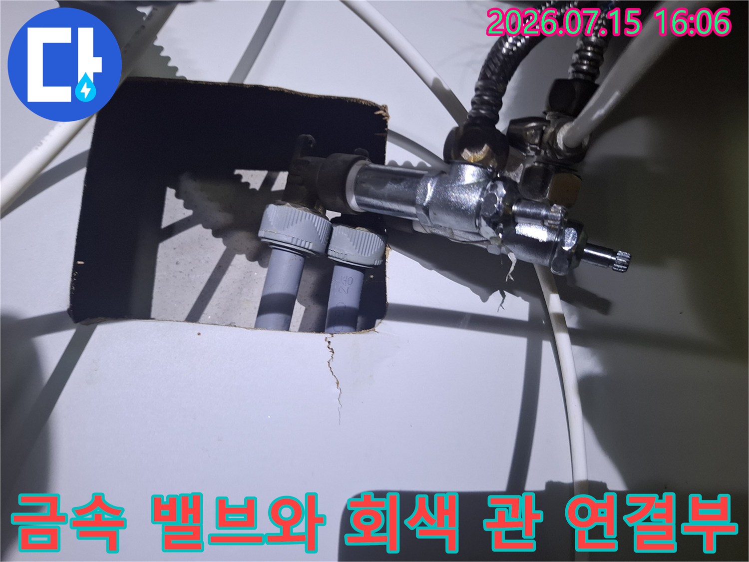 회색 플라스틱 파이프가 금속제 누수 차단 밸브에 연결되어 있는 상세 사진