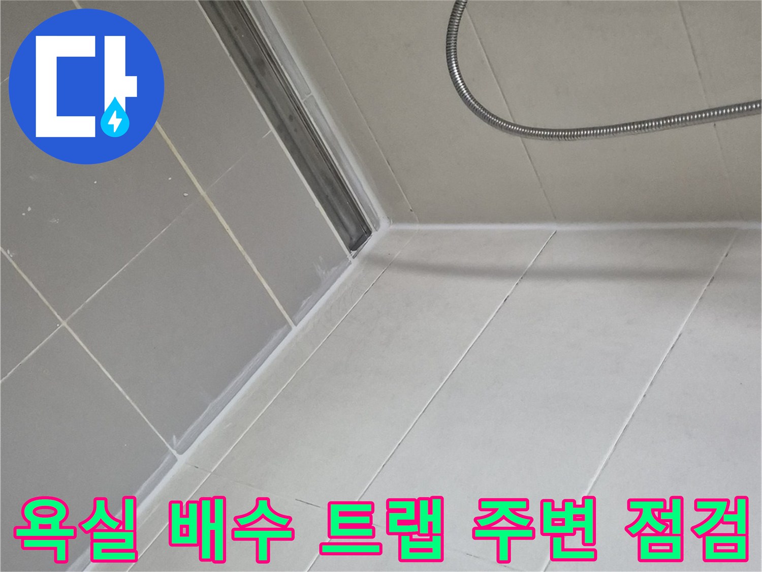 배수구가 설치된 화장실 바닥 타일과 샤워기 호스 연결 부위입니다.