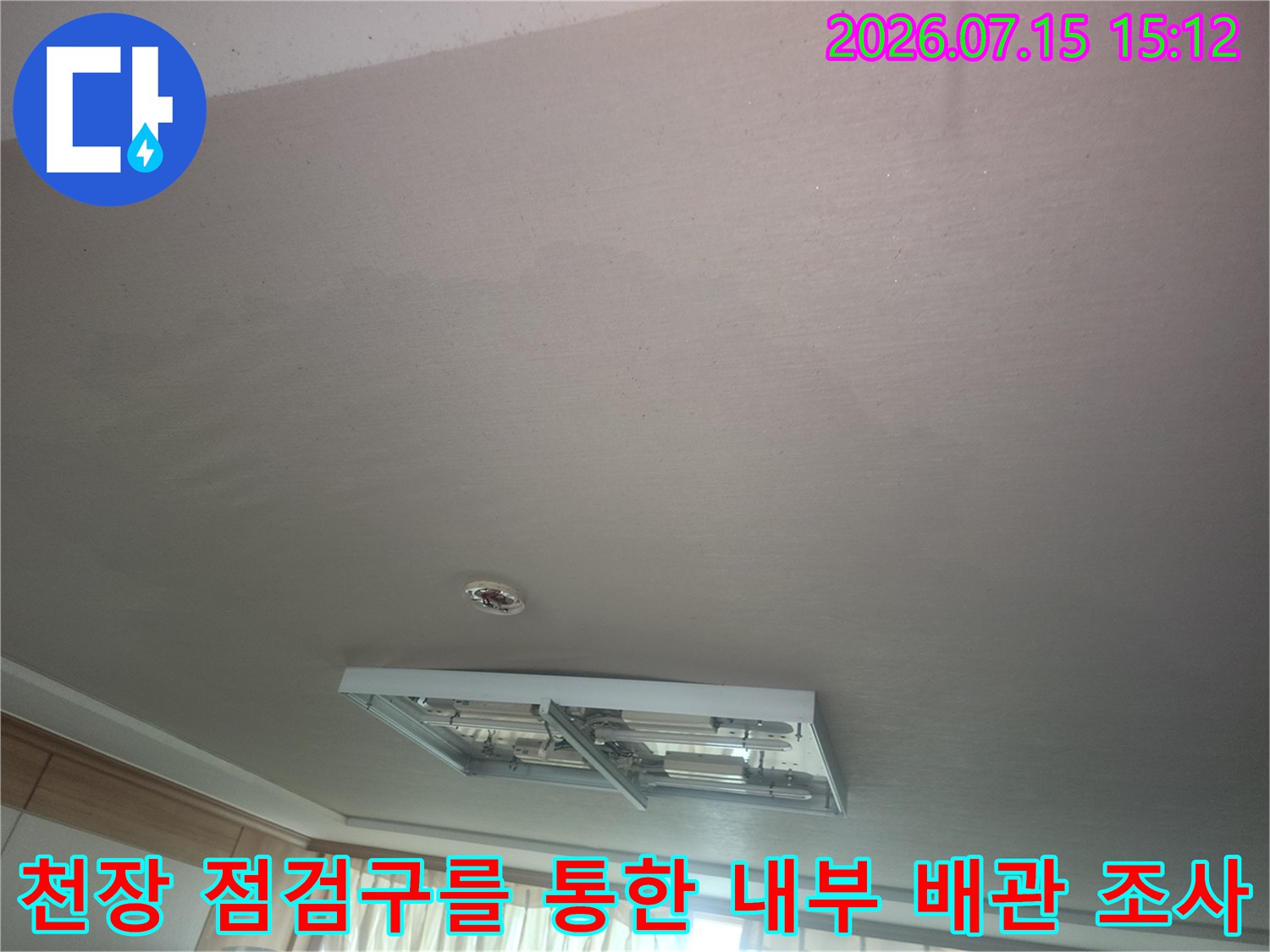 천장의-점검구가-열려있고-내부의-금속제-배관들이-노출된-상태