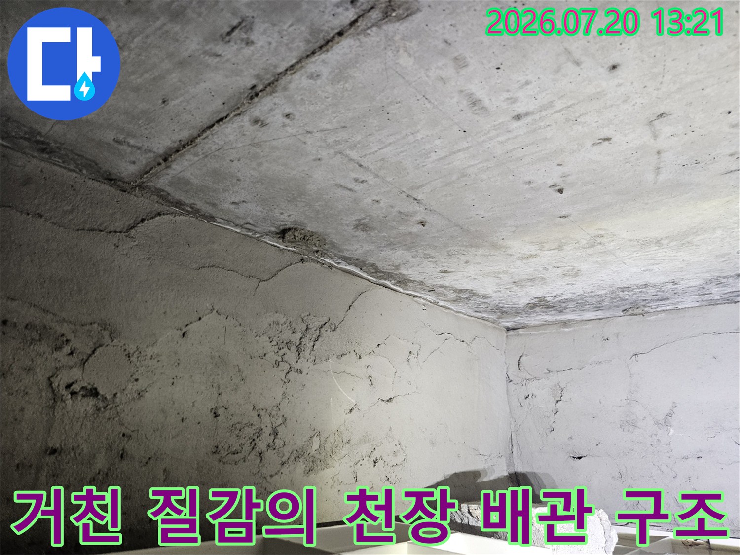 먼지가 쌓인 콘크리트와 노출된 배관이 얽힌 천장 내부 모습