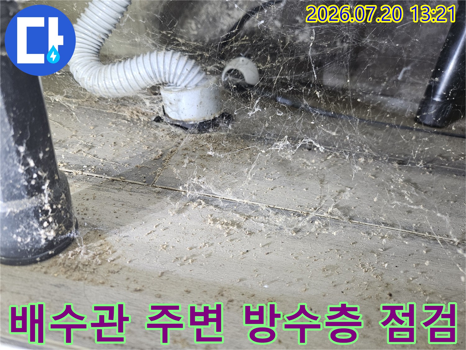 흰색 플라스틱 배관과 세탁 호스가 겹쳐진 구간의 누수 흔적을 촬영한 사진