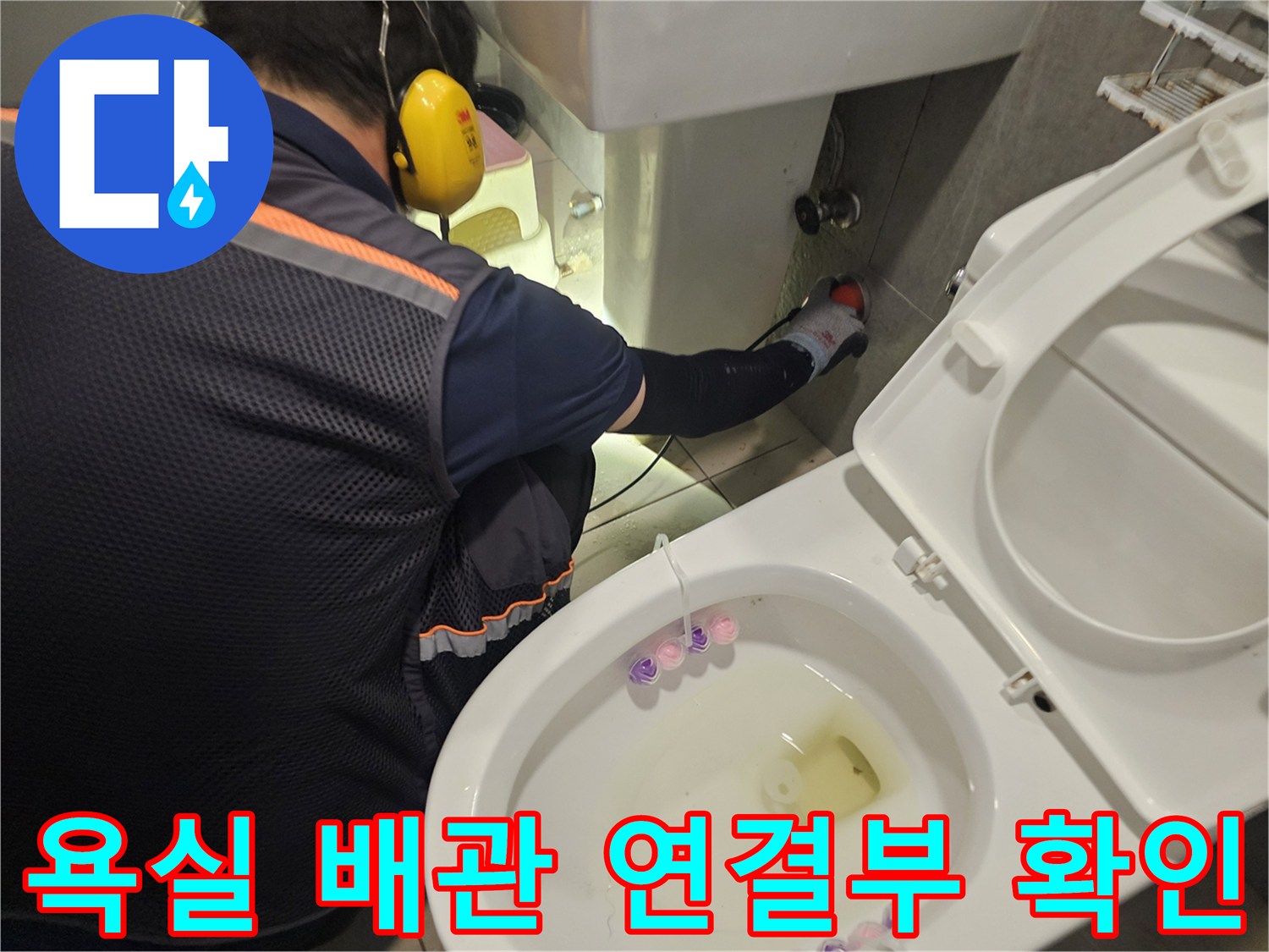 변기 근처 세면대 아래 배관 부속을 점검하는 엔지니어의 작업 모습