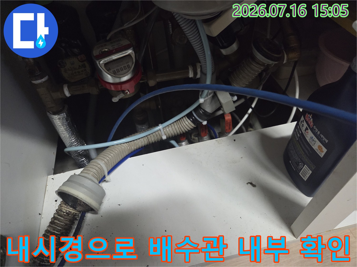 싱크대 하부장 아래 배치된 배수관과 내시경 장비를 연결하여 내부를 점검하는 모습