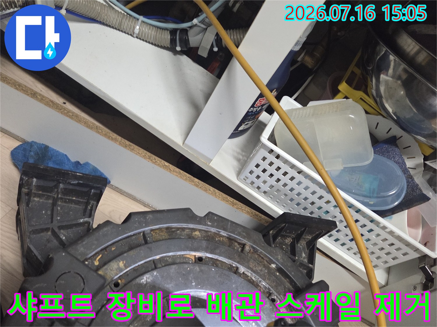 전동 샤프트 기기를 활용하여 싱크대 하단부 배수관의 찌꺼기를 분쇄하는 장면