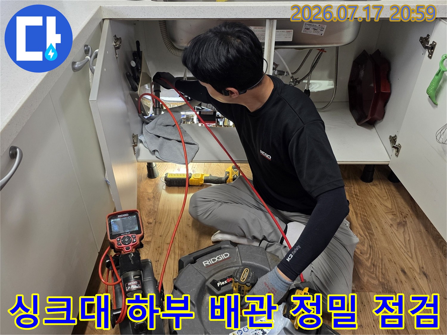 엔지니어가 싱크대 아래 공간에서 전문 장비를 사용하여 배관을 정밀하게 점검하는 모습