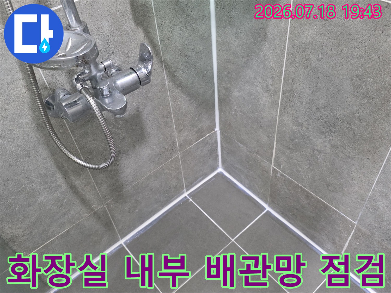 그레이 톤 타일벽과 샤워용 수전 및 호스가 설치된 구간