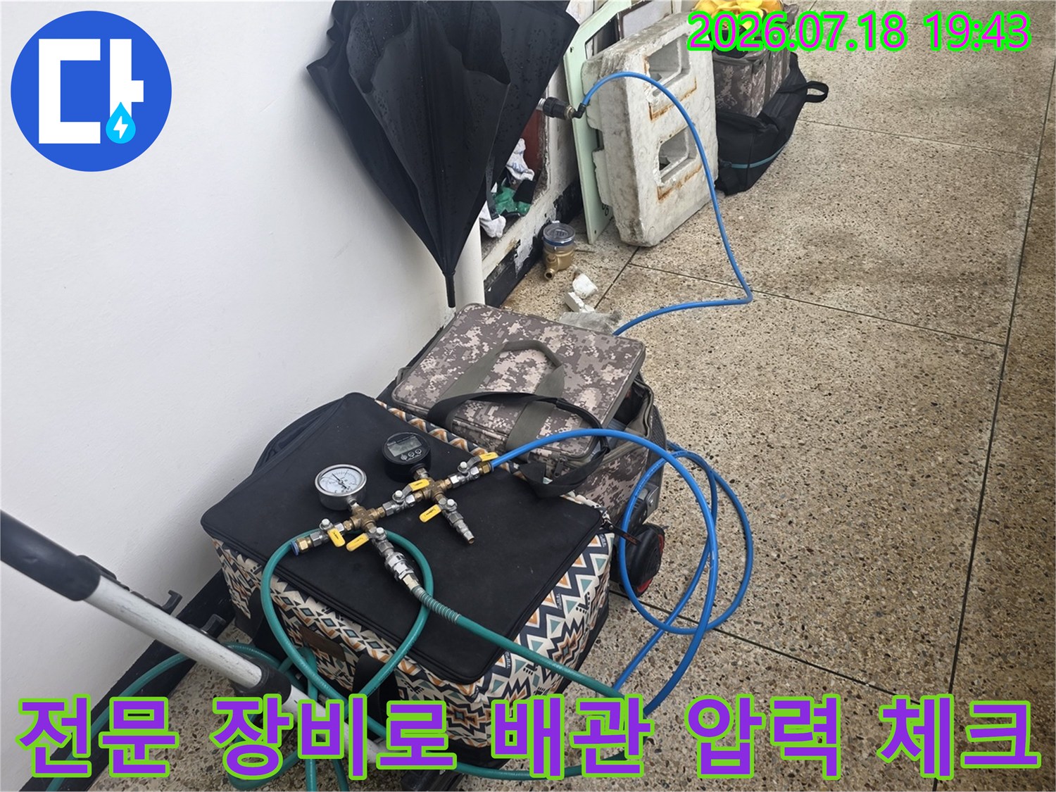 다양한 호스가 연결된 전문 누수 탐지용 압력 측정기 세팅 장면