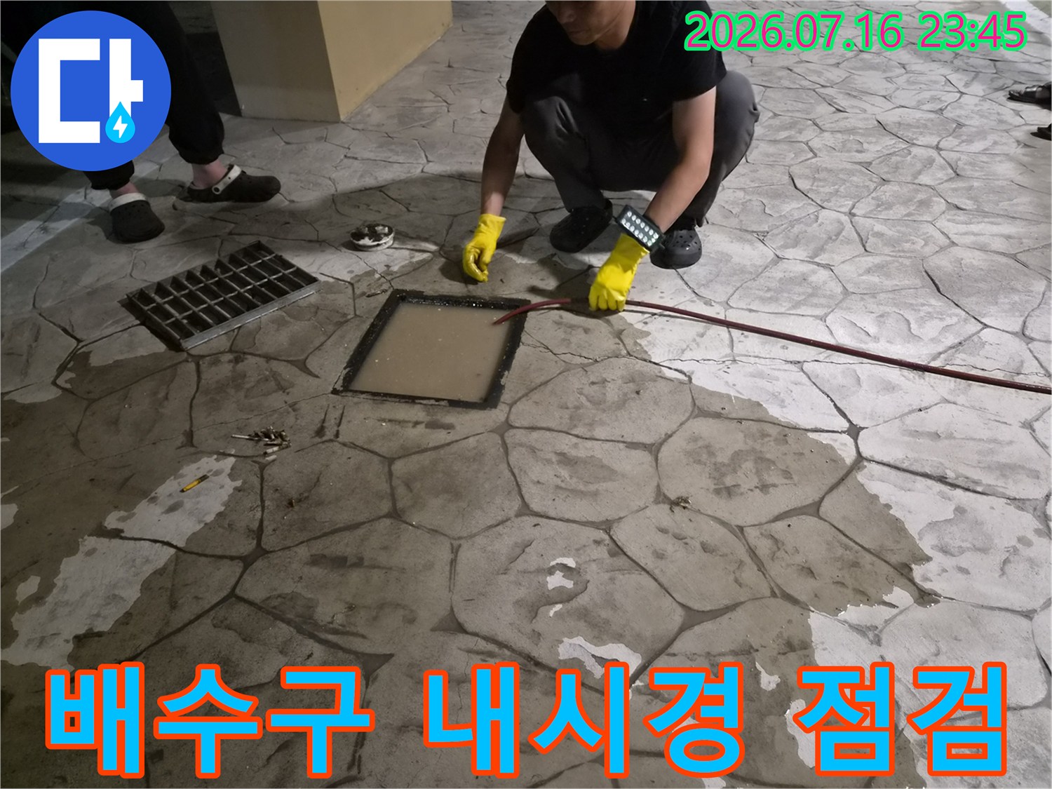 노란 장갑을 낀 작업자가 배수구 내부를 확인하기 위해 내시경 장비를 투입하는 모습