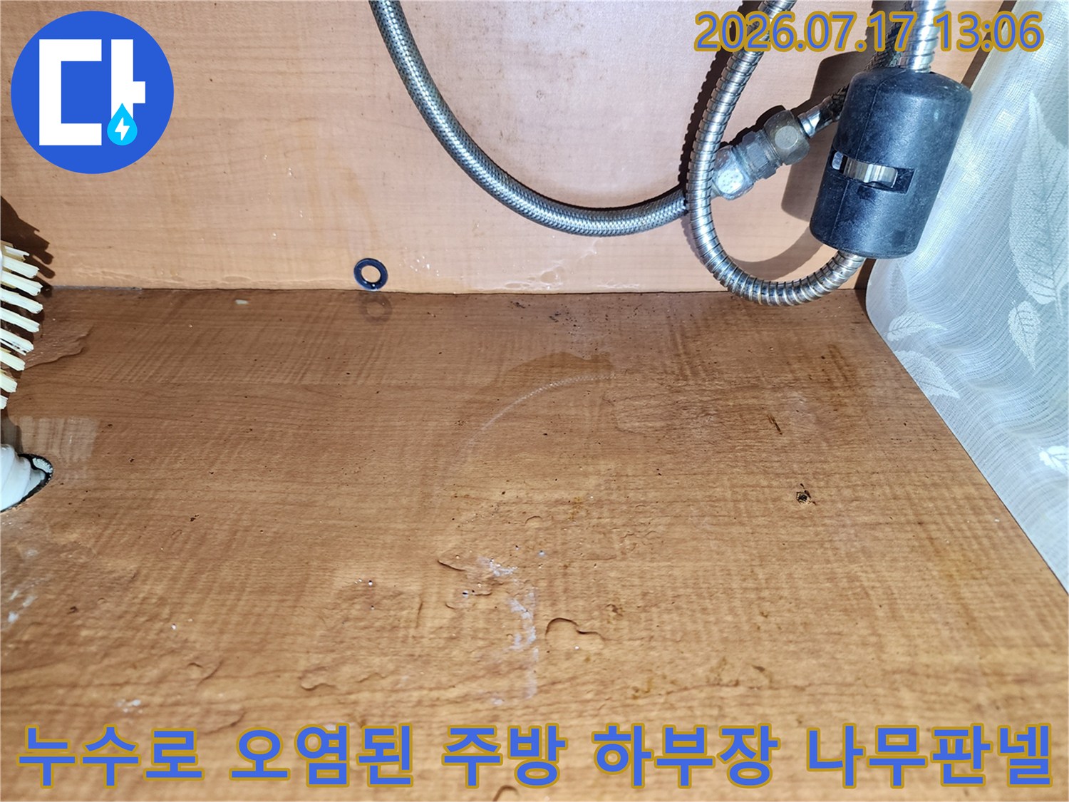 물기가 스며들어 표면 색상이 짙게 변하고 얼룩진 싱크대 내부의 목재 자재