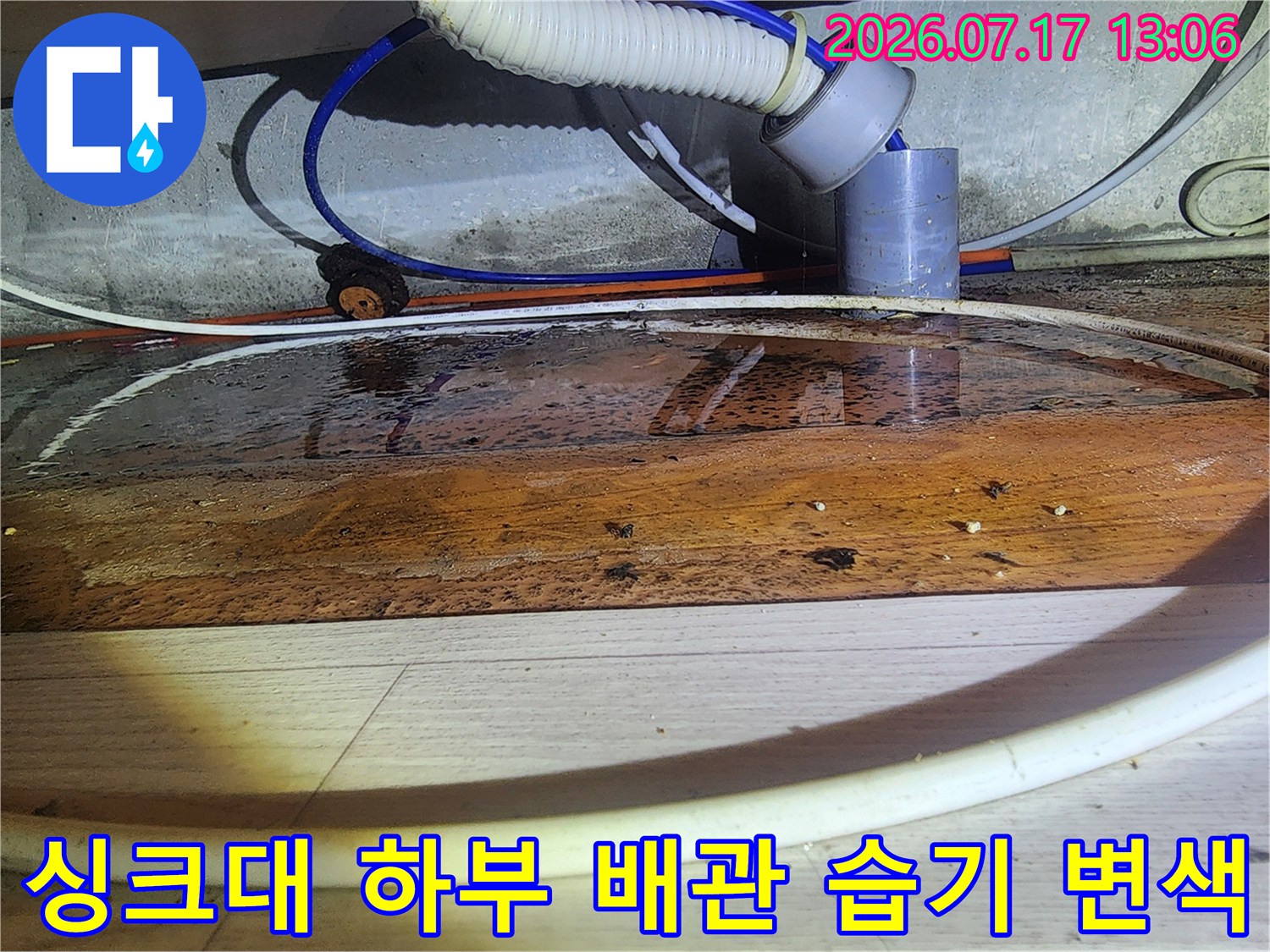 주방 싱크대 아래쪽 목재 판넬이 누수로 인해 짙게 변색된 모습-배관 연결 부위 중심