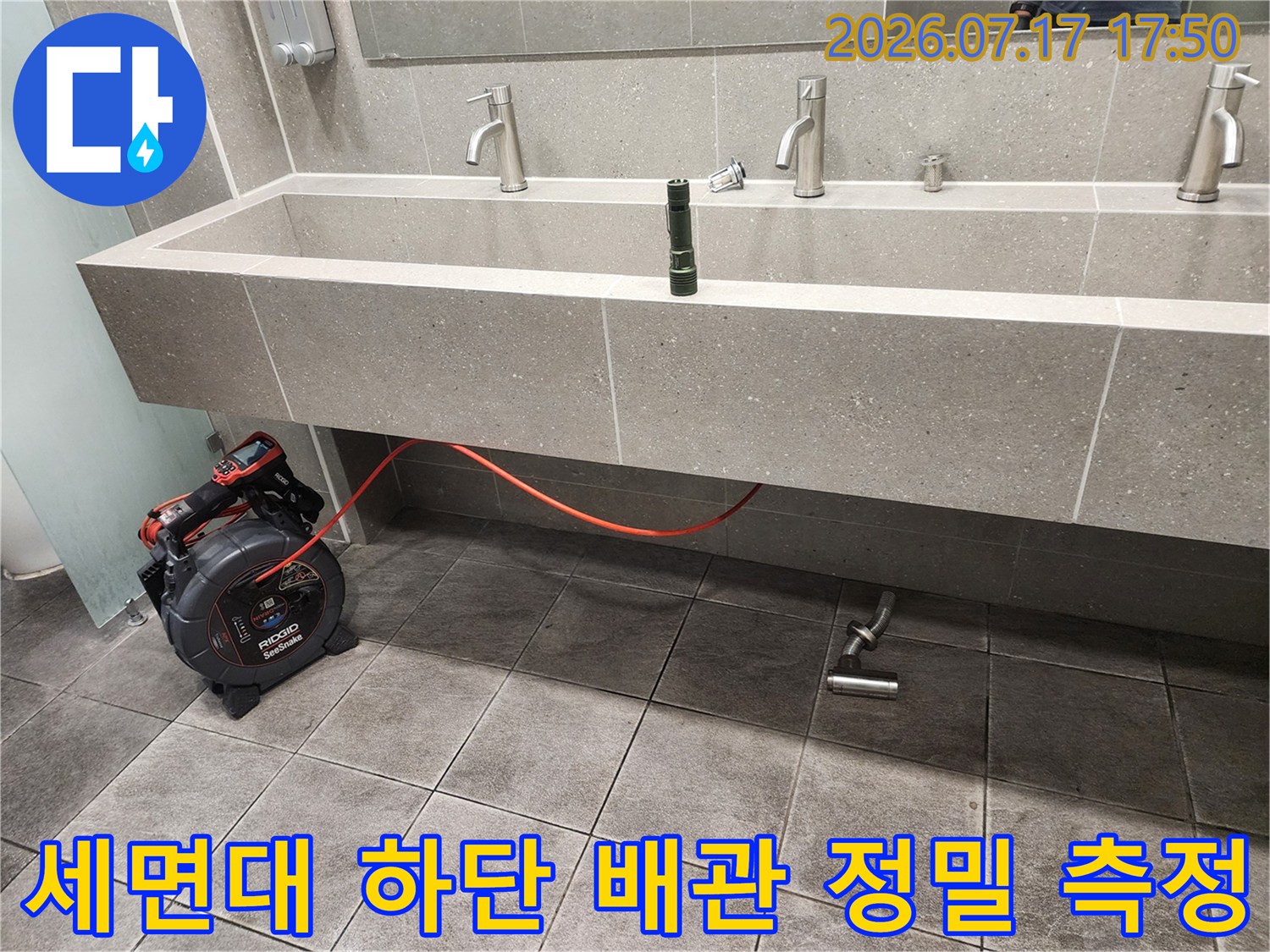 회색 톤의 욕실 내부 세면대 아래쪽으로 설치된 누수 탐지 장치와 연결선