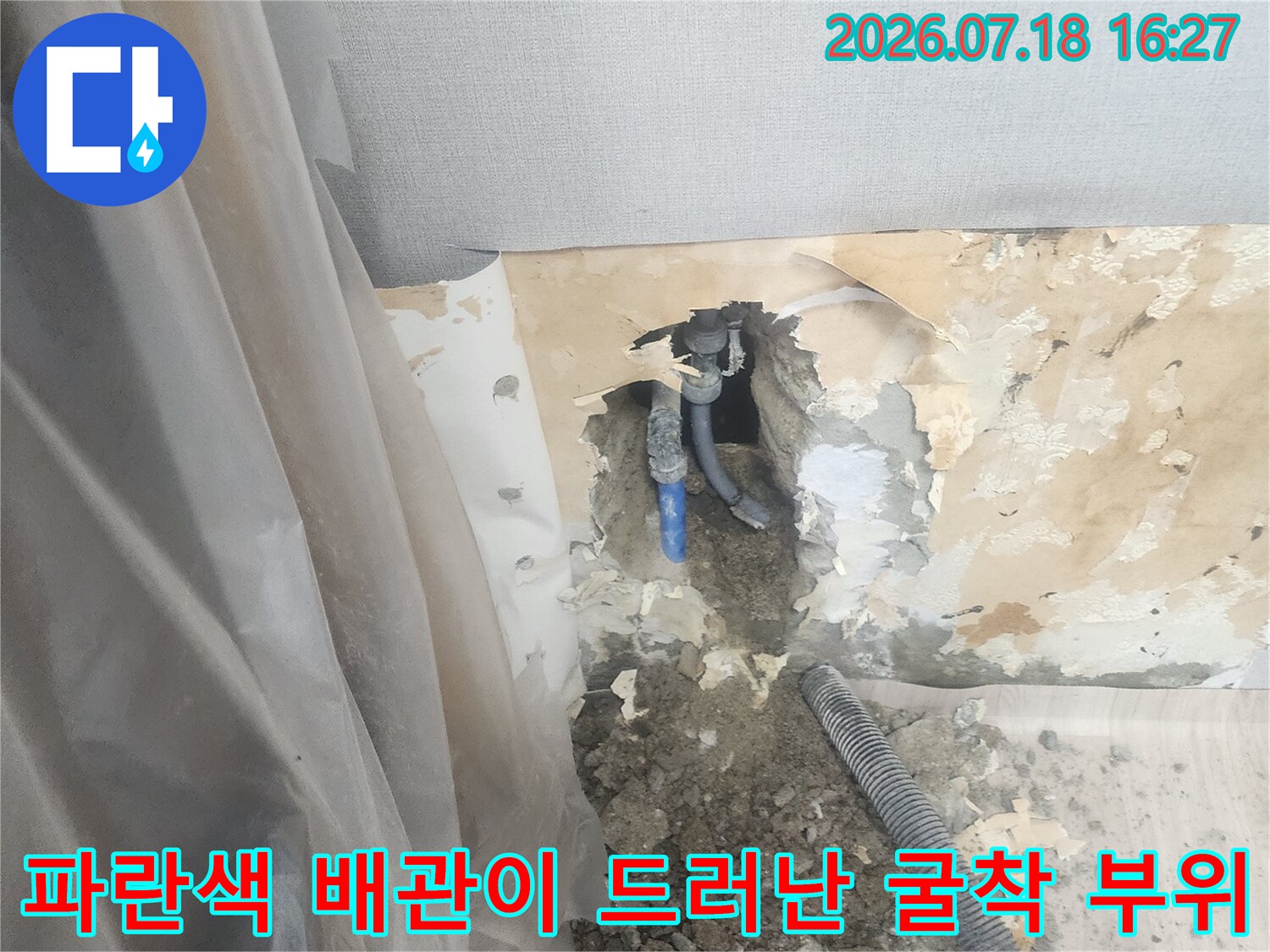 콘크리트와 흙이 섞인 굴착 지점에서 파란색 수도관이 노출된 사진-누수 탐지 완료