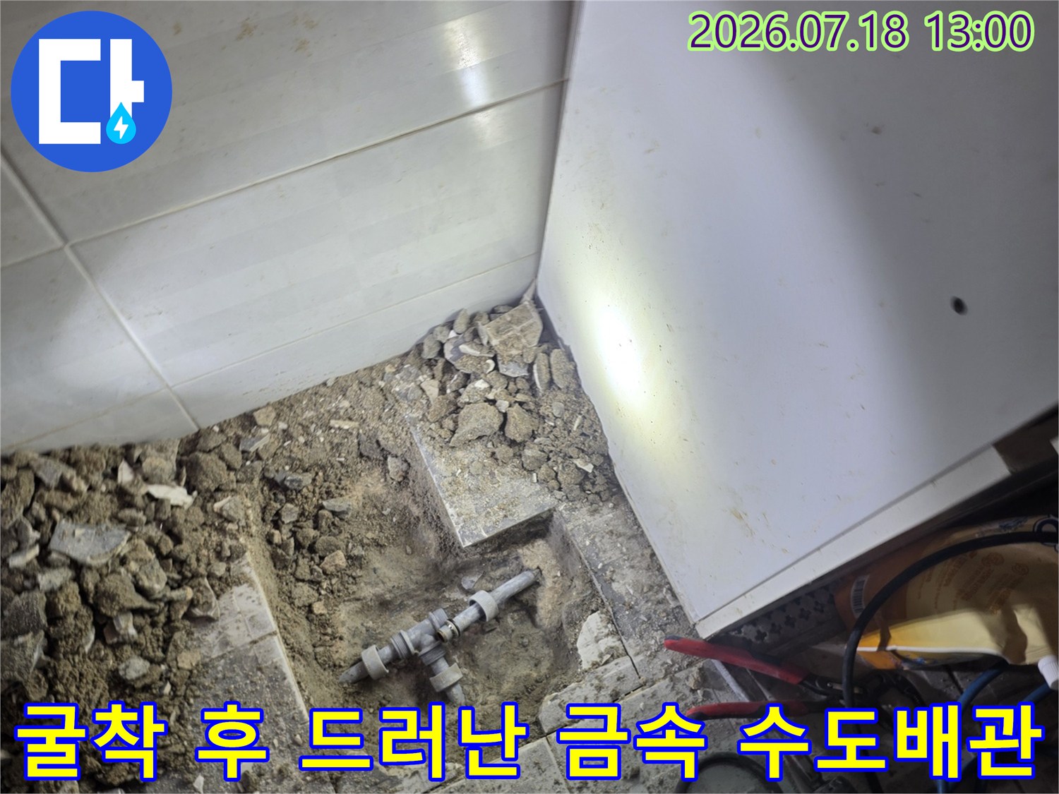 바닥 타일과 콘크리트 층을 파내어 드러난 L자형 금속 배관 연결 부위-작업 사진