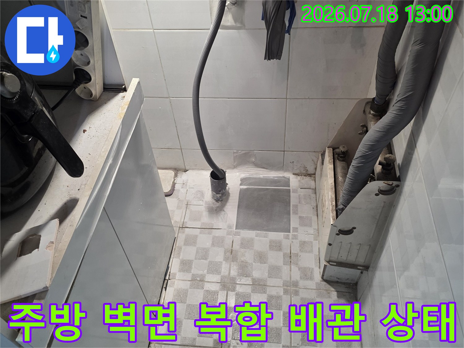 타일 벽면에 설치된 회색 보온재 배관과 노란색 호스가 얽혀 있는 모습
